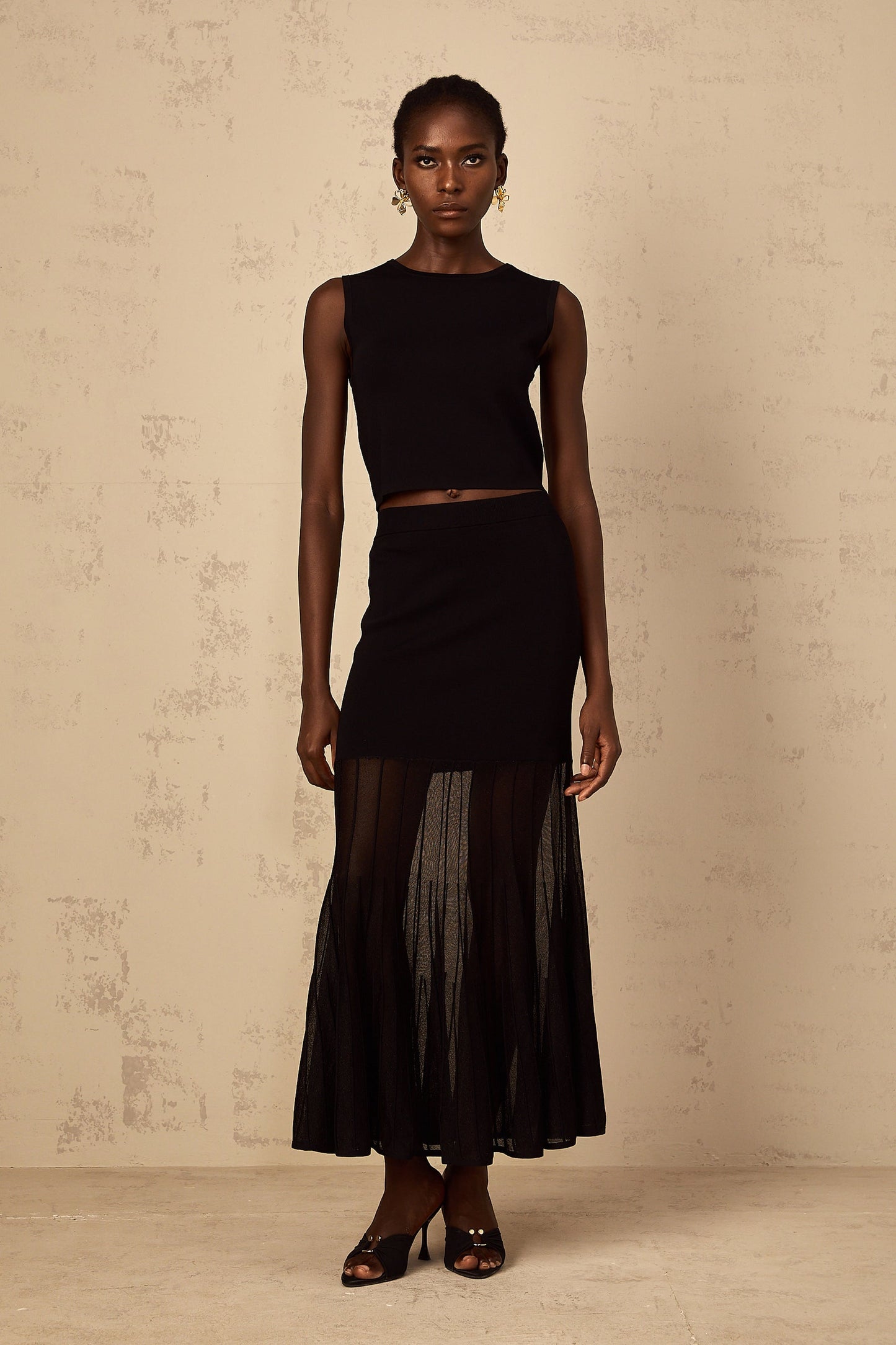 A woman wearing a black fine knit matching set with panelled details consisting of a top and bottoms