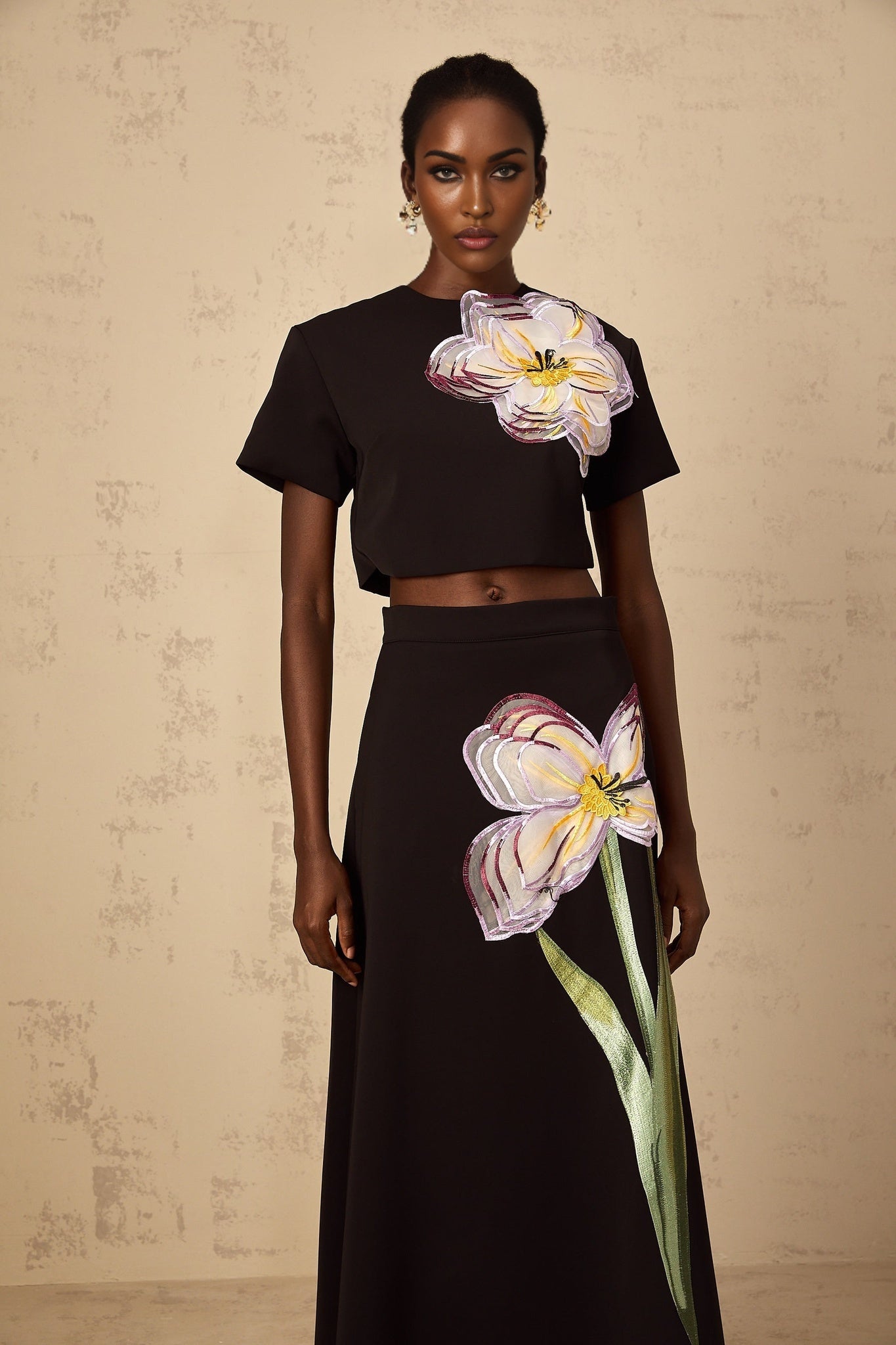 A woman wearing a black matching set featuring sequin floral embroidery on both the top and bottom pieces