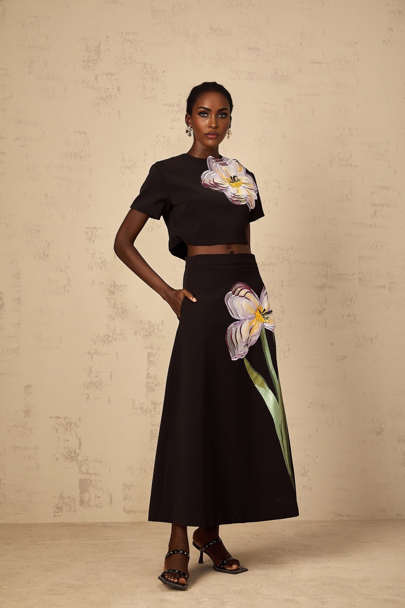 A woman wearing a black matching set with sequin floral embroidery consisting of a top and pants