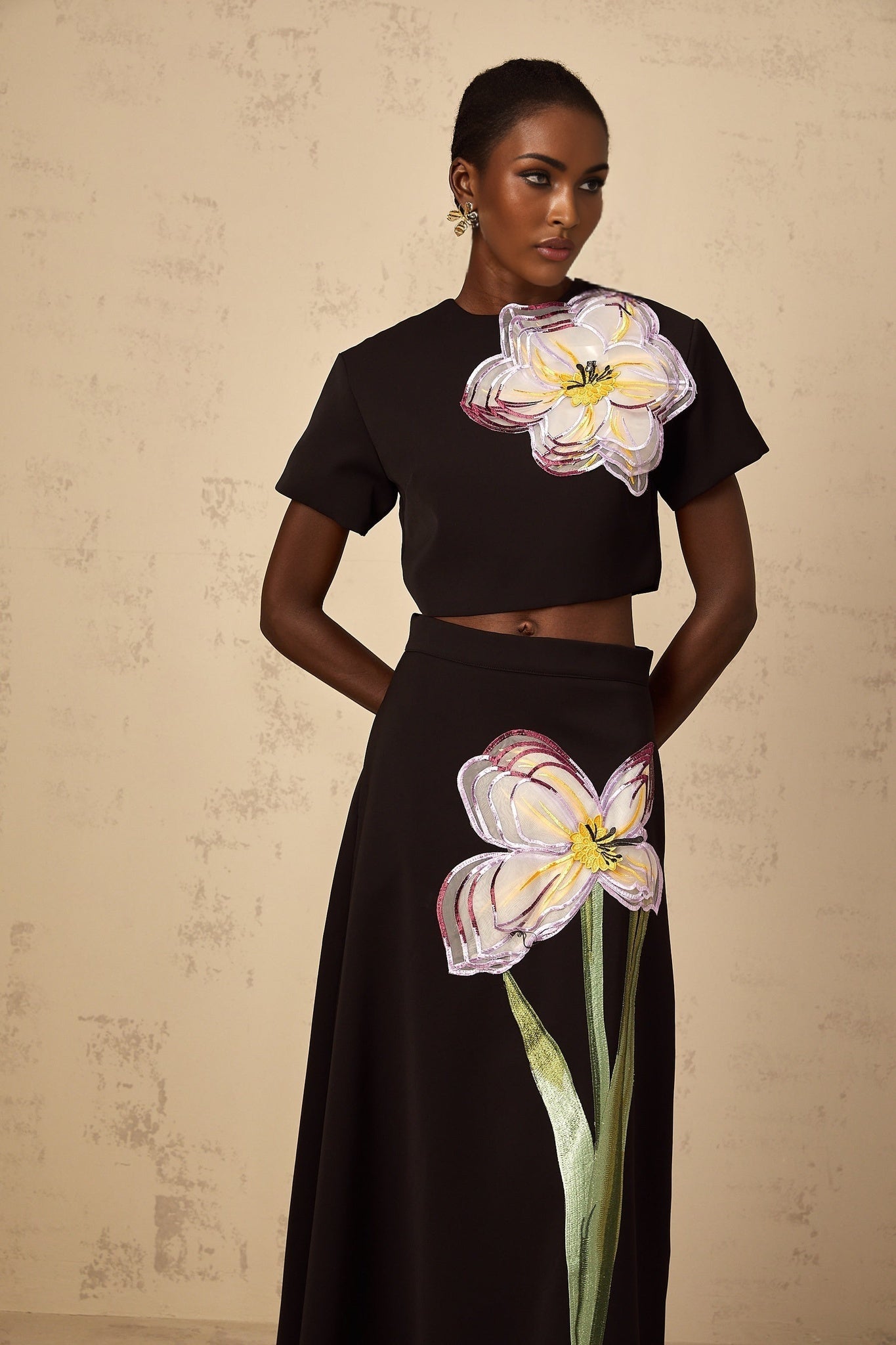 A woman wearing a black sequin matching set with floral embroidery consisting of a top and bottom piece