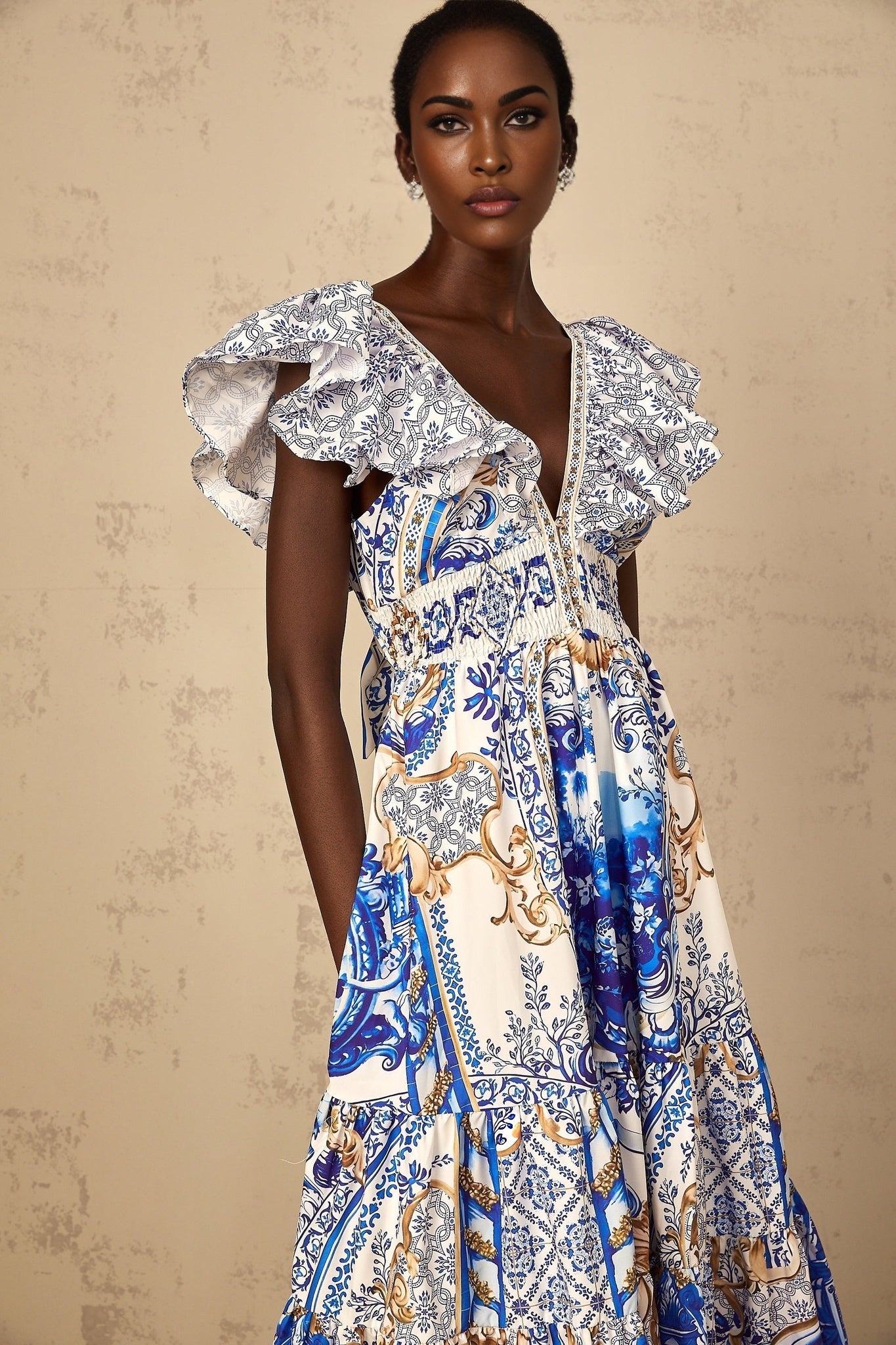 A woman wearing a blue midi dress with a baroque print pattern and tiered design