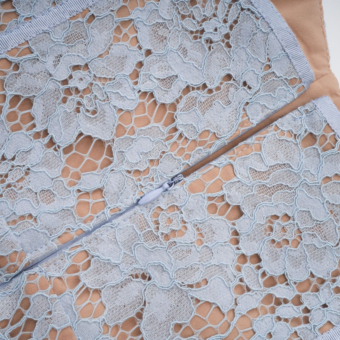 A woman wearing a blue midi dress with floral lace pattern and boned bodice
