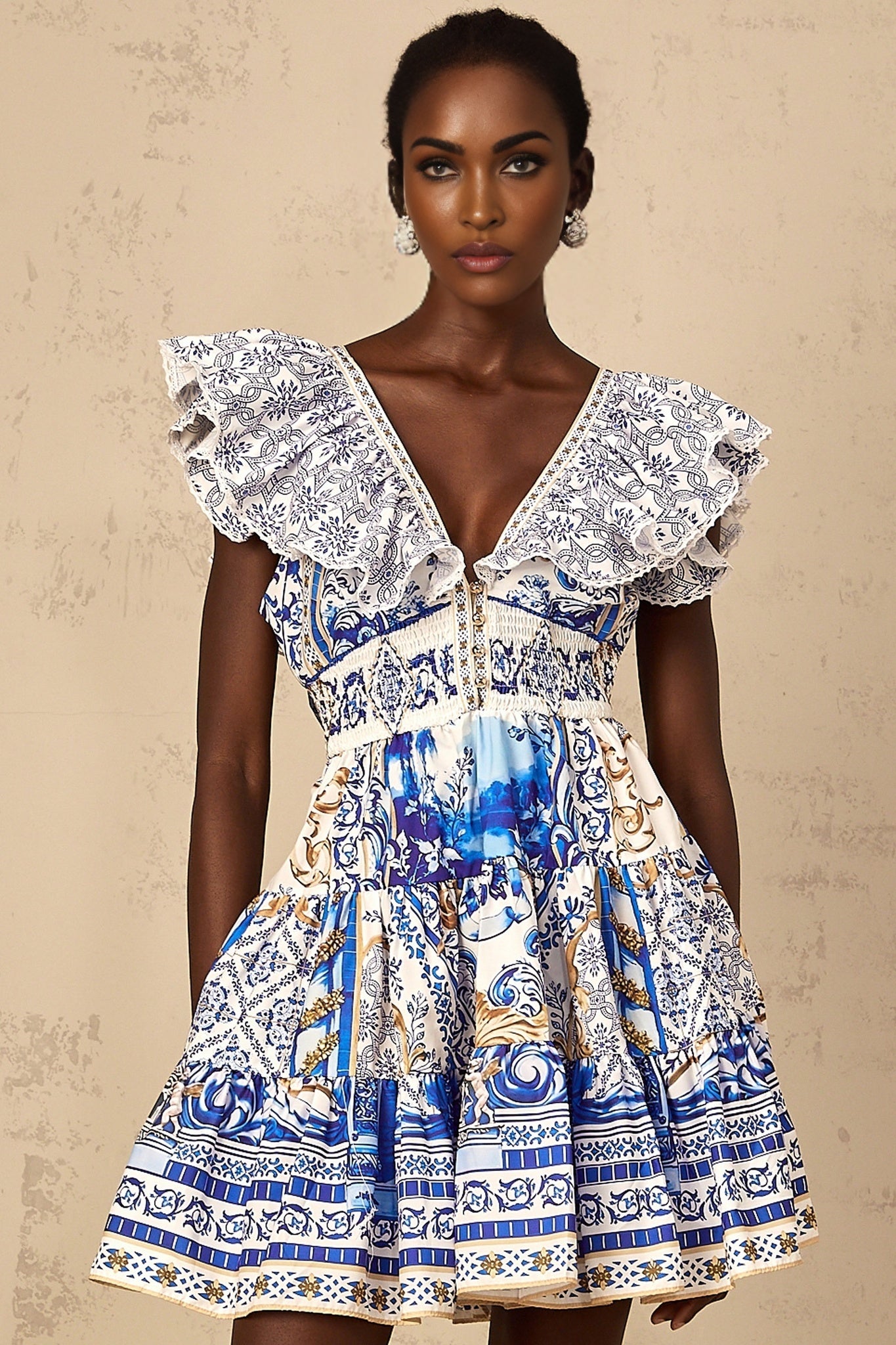 A woman wearing a blue mini dress with a baroque print pattern and tiered layers
