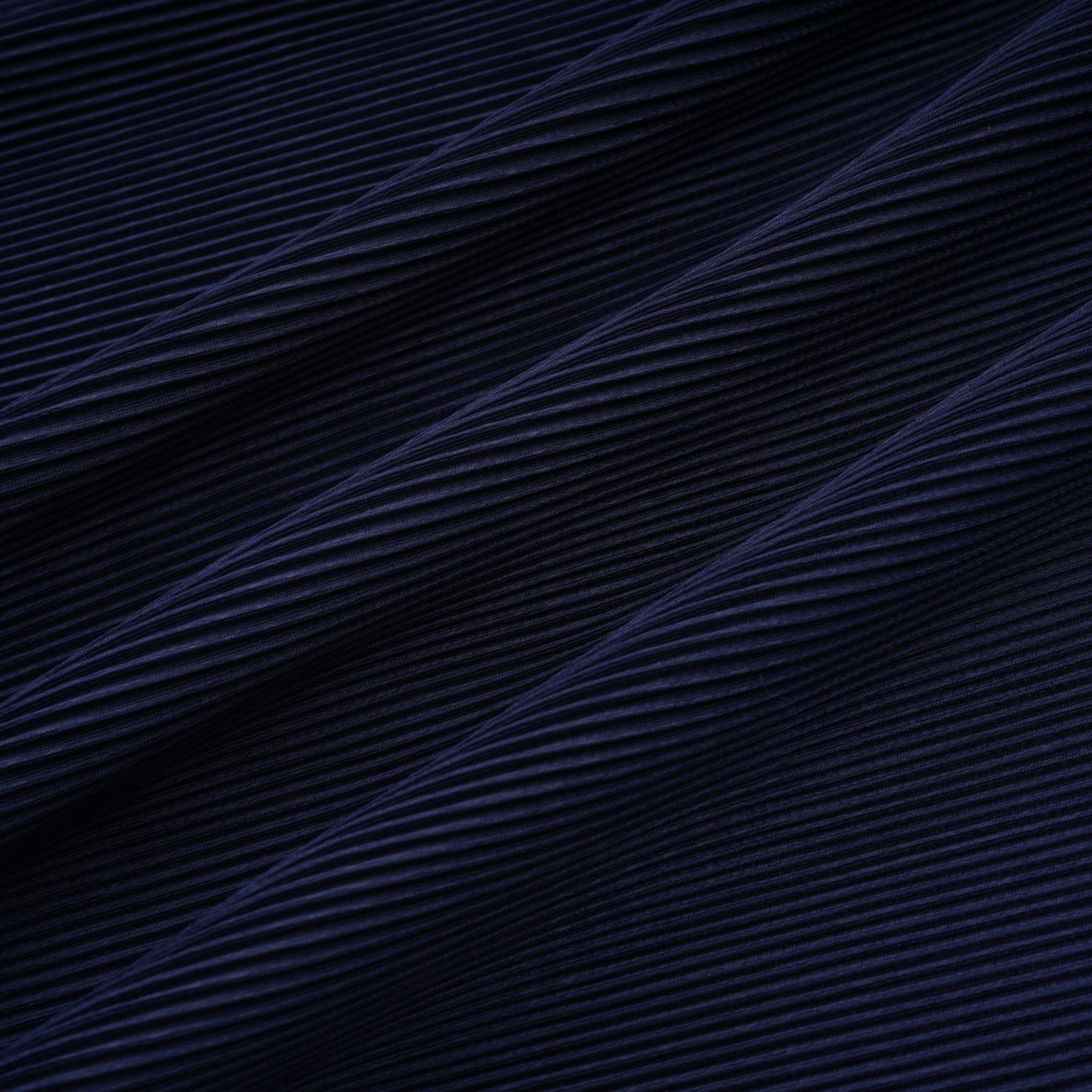 A woman wearing a blue patterned cape and matching skirt set Debbie model The cape is creased and flows over the shoulders The skirt is fitted and falls below the knee Both pieces feature a repeating print pattern in shades of blue