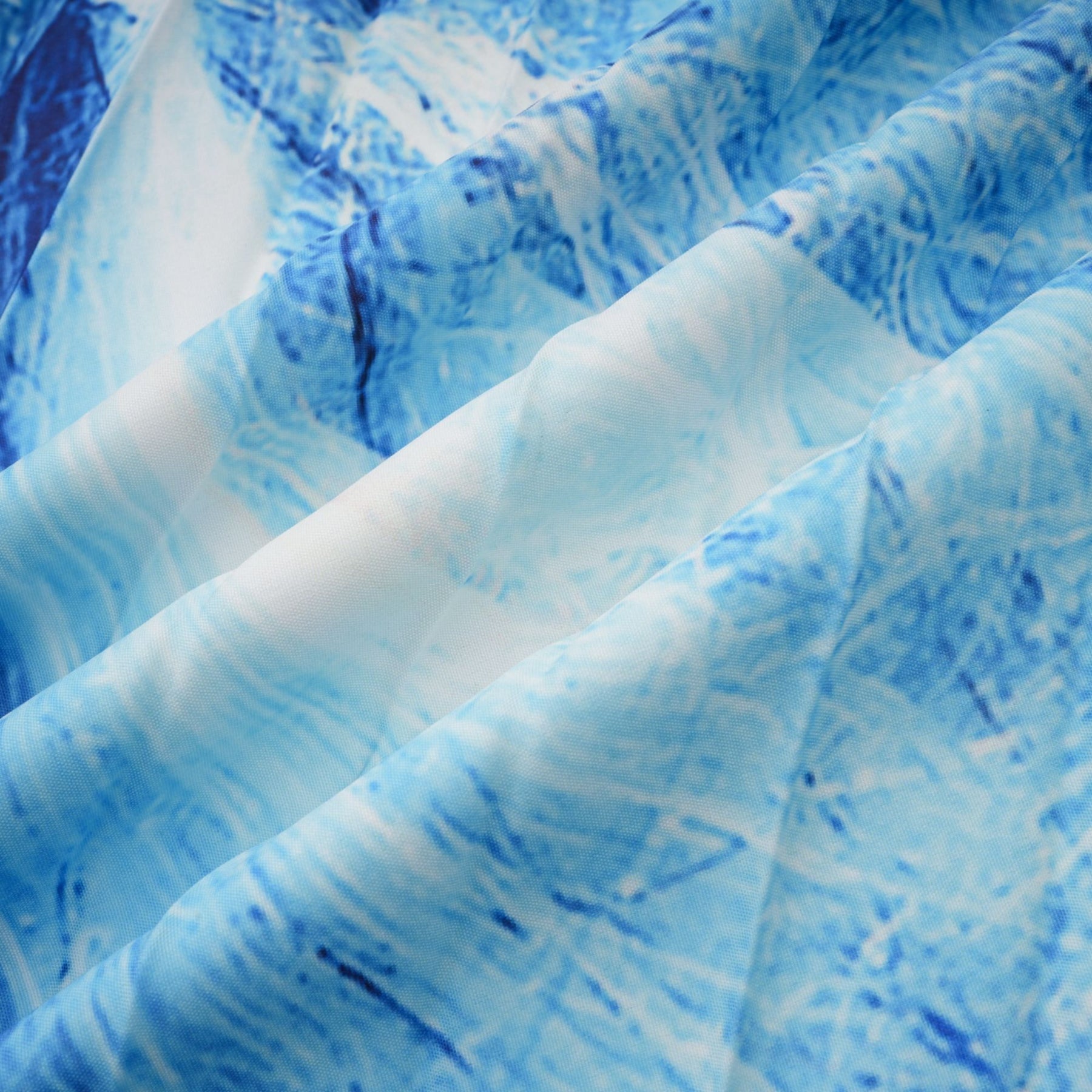 A woman wearing a blue patterned cape and matching skirt set The cape is creased and drapes elegantly over the shoulders The skirt falls to mid calf length Both pieces feature a repeating print pattern in shades of blue