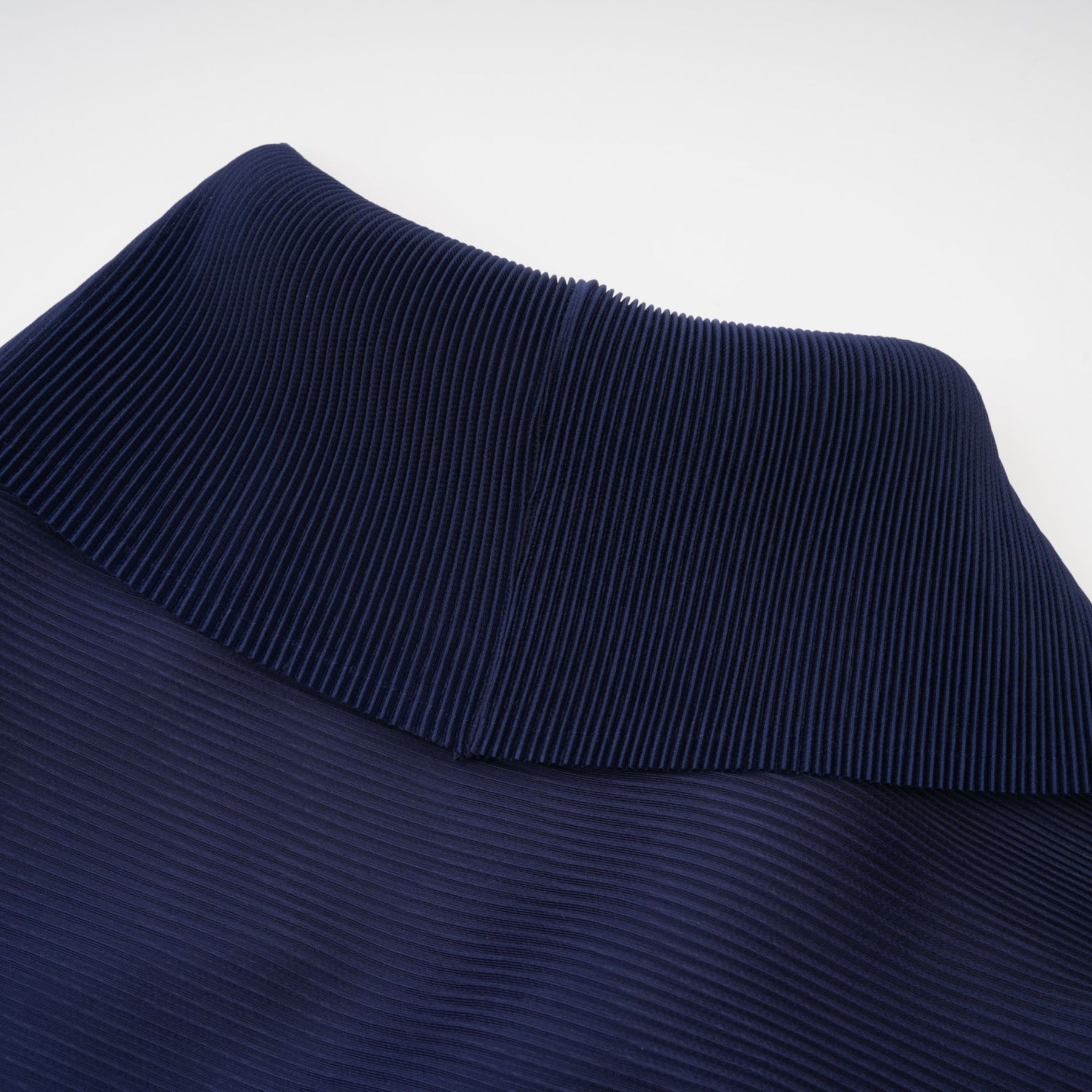 A woman wearing a blue patterned cape and matching skirt set The cape is creased and flows over the shoulders while the skirt falls to mid calf Both pieces feature a bold allover print design in shades of blue