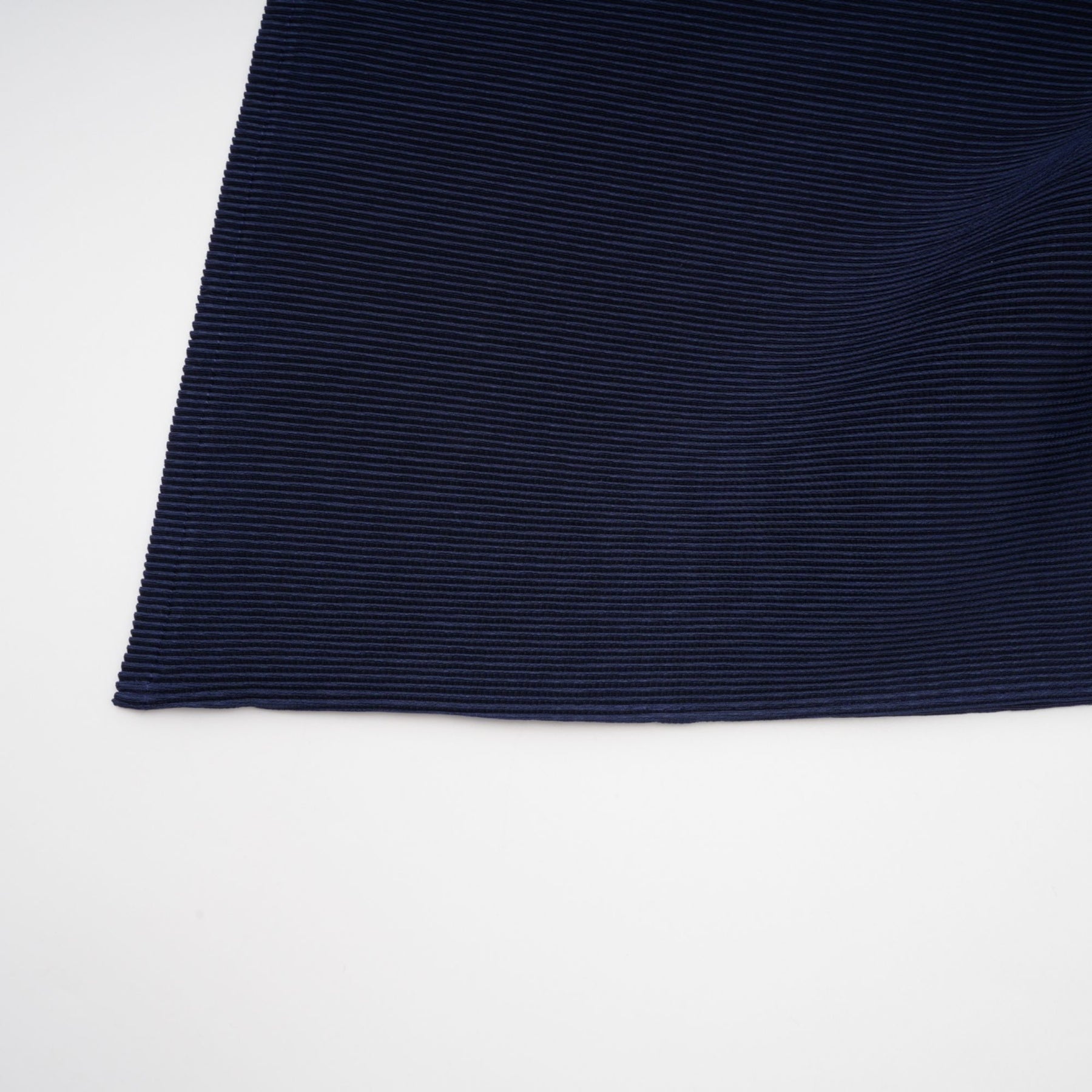 A woman wearing a blue patterned cape and matching skirt set The cape is loose fitting with a creased texture and the skirt falls to mid length Both pieces feature a bold printed pattern in shades of blue