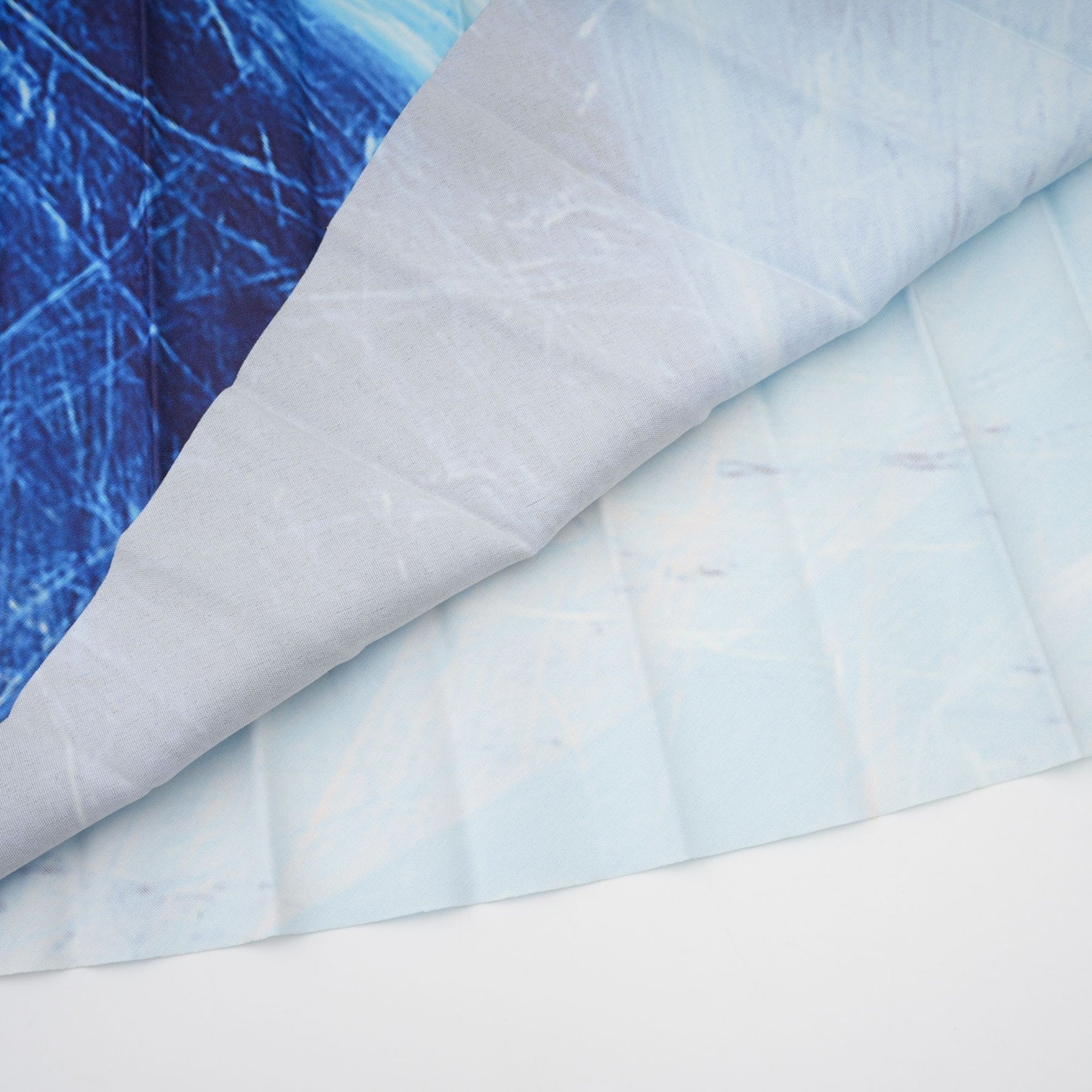 A woman wearing a blue patterned matching set consisting of a flowing cape and a skirt The cape drapes over the shoulders and the skirt falls to mid calf Both pieces feature a crinkled texture and an allover abstract print in shades of blue