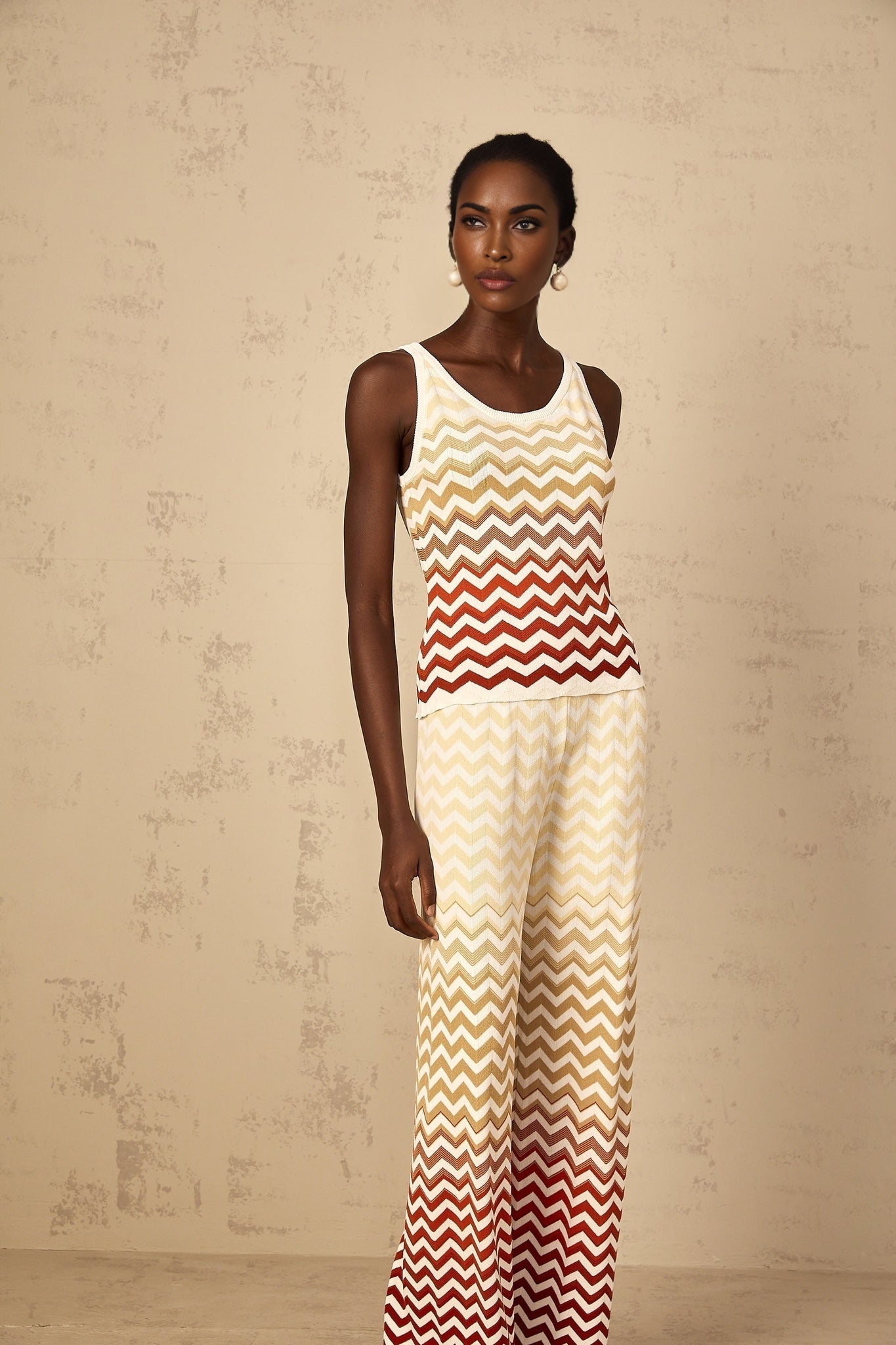 A woman wearing a bright yellow knit two piece outfit with a zigzag pattern consisting of a cropped top and matching shorts