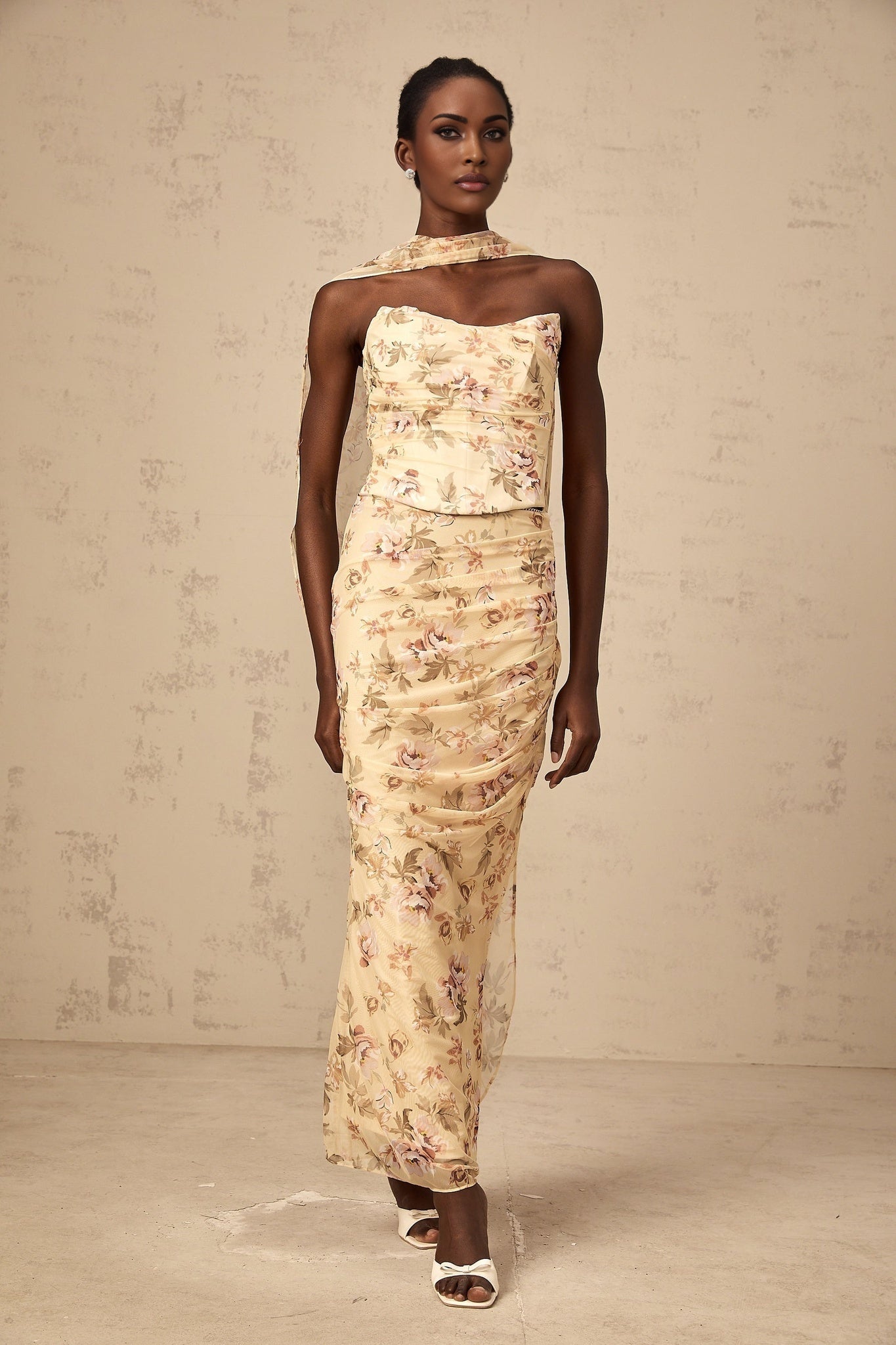 A woman wearing a bright yellow twopiece outfit with a floral print design consisting of a fitted top and matching skirt