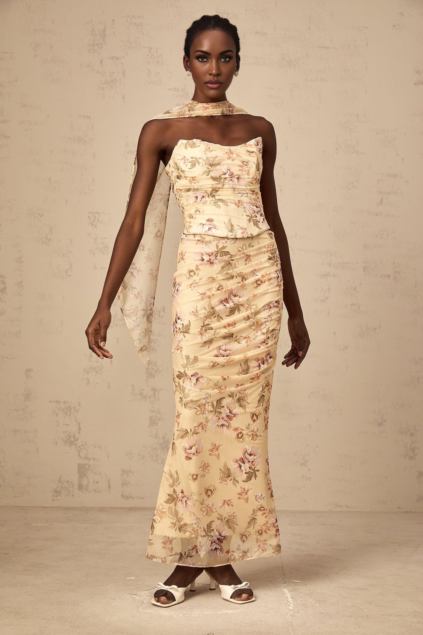 A woman wearing a bright yellow twopiece outfit with a floral print featuring a fitted top and matching skirt