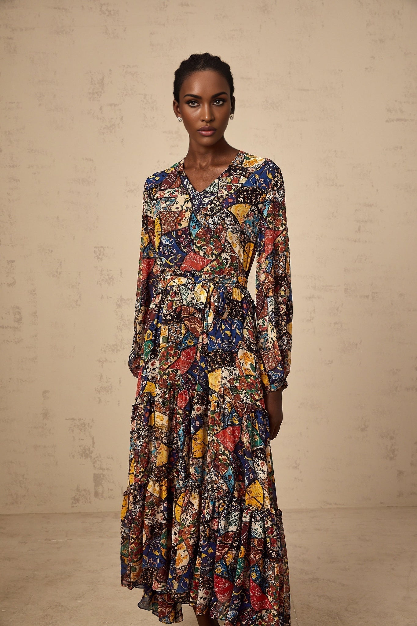 A woman wearing a brown bohemian style midi dress with shirring detail and flowing fabric standing in a casual pose