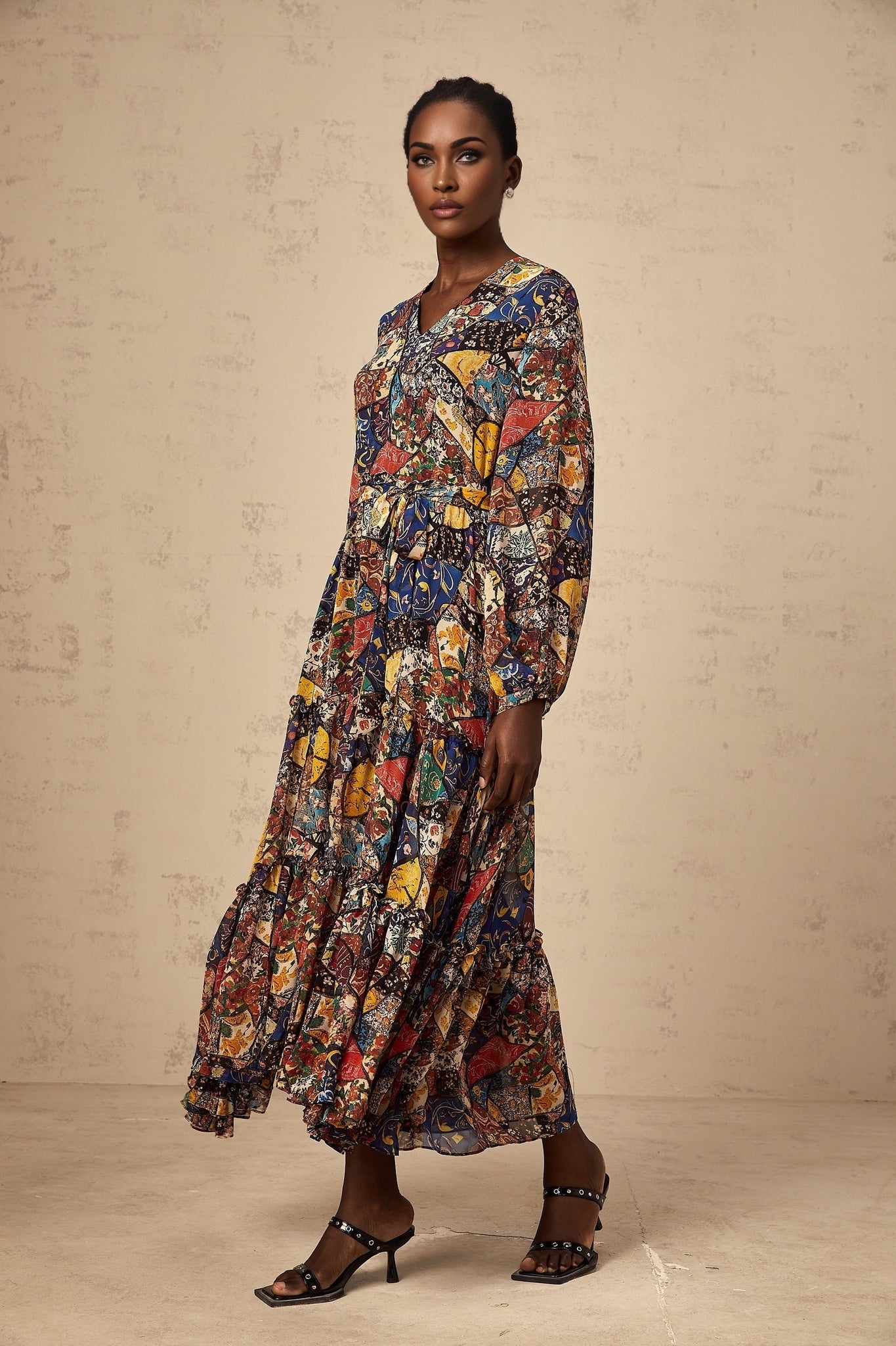 A woman wearing a brown bohemian style midi dress with shirring details and a flowing silhouette