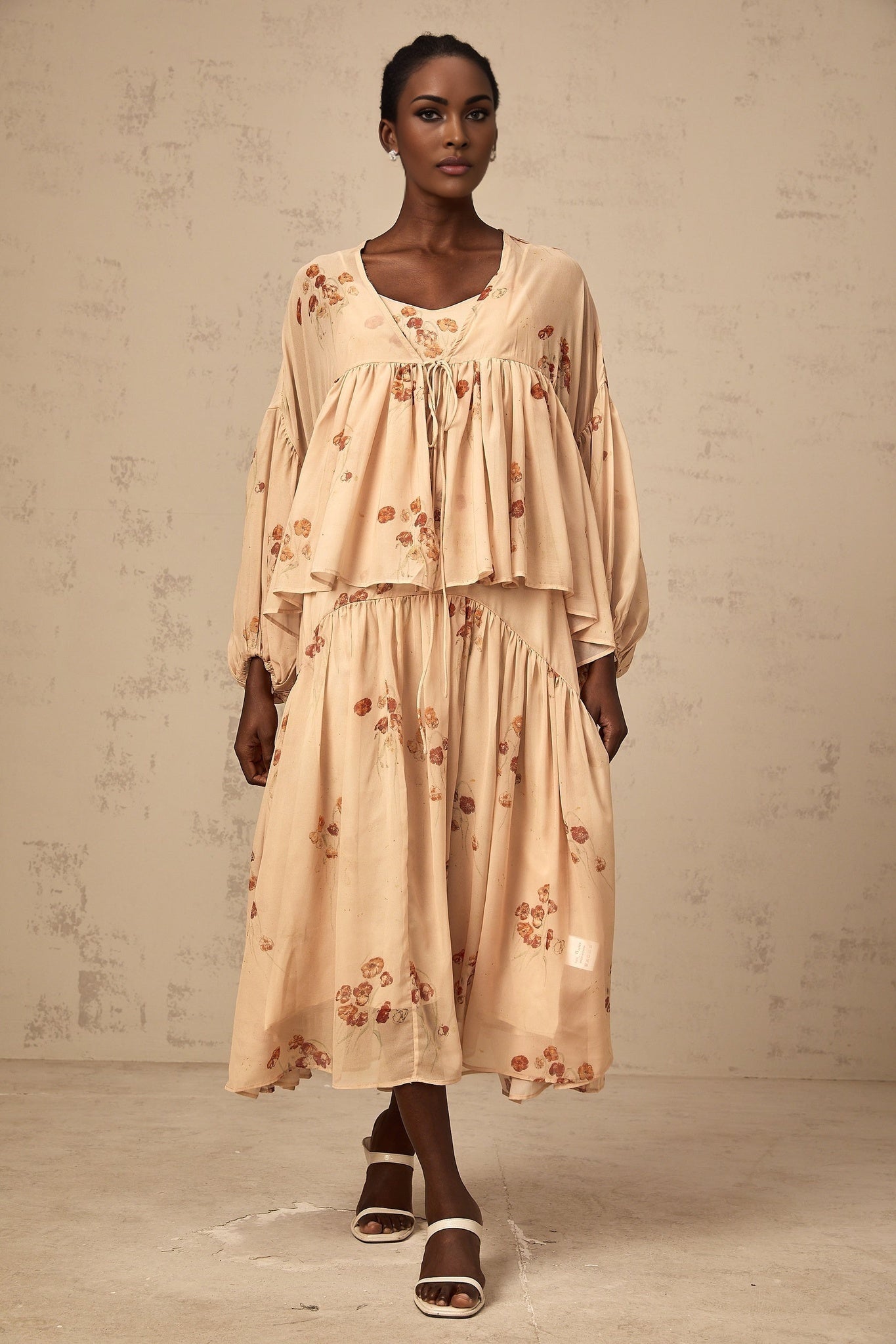 A woman wearing a coralpink floral print matching set consisting of a pleated blouse and dress The outfit has a summery and feminine appearance