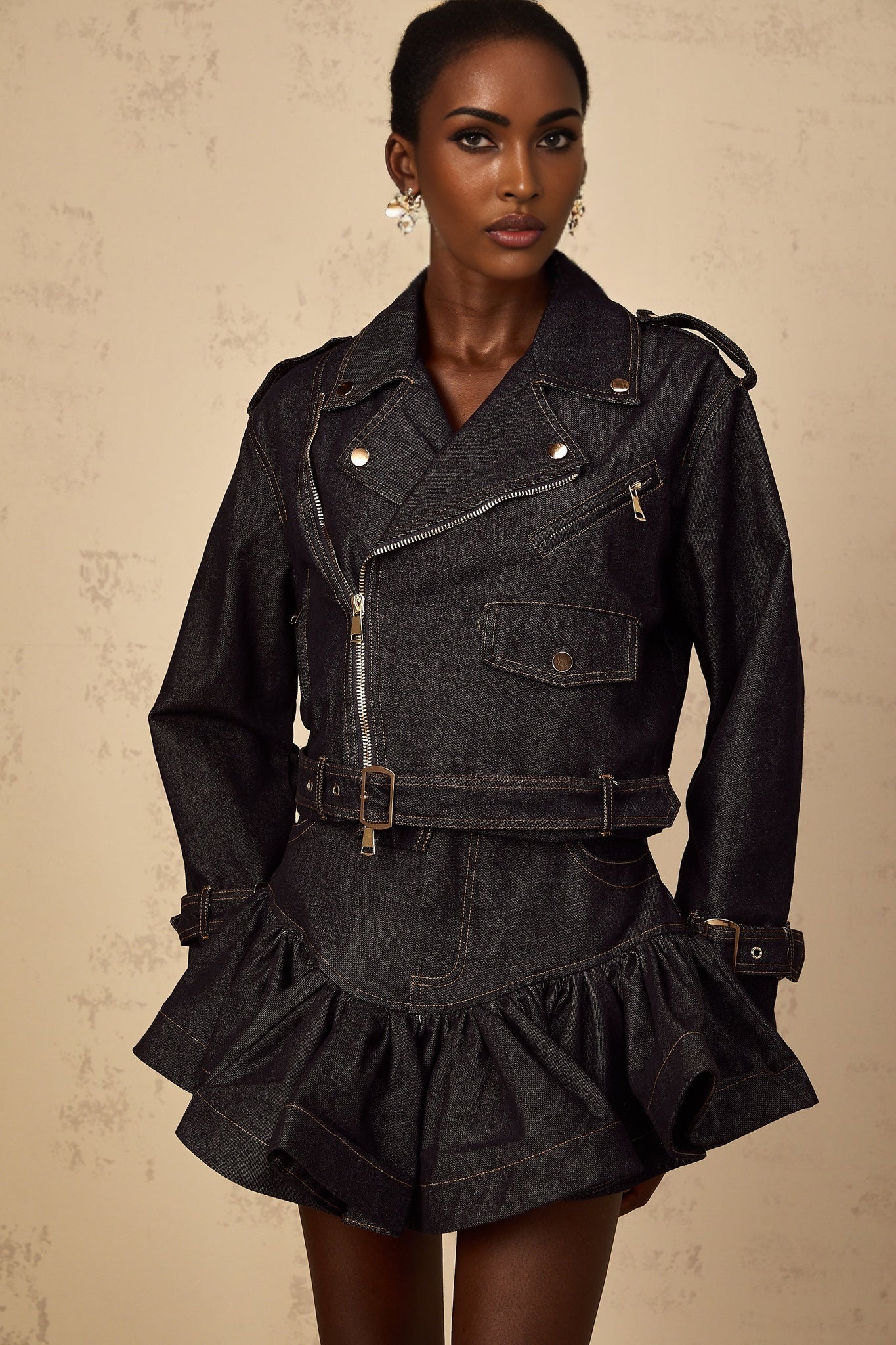A woman wearing a dark indigo blue denim jacket with visible light colored contrast stitching along the seams and pockets