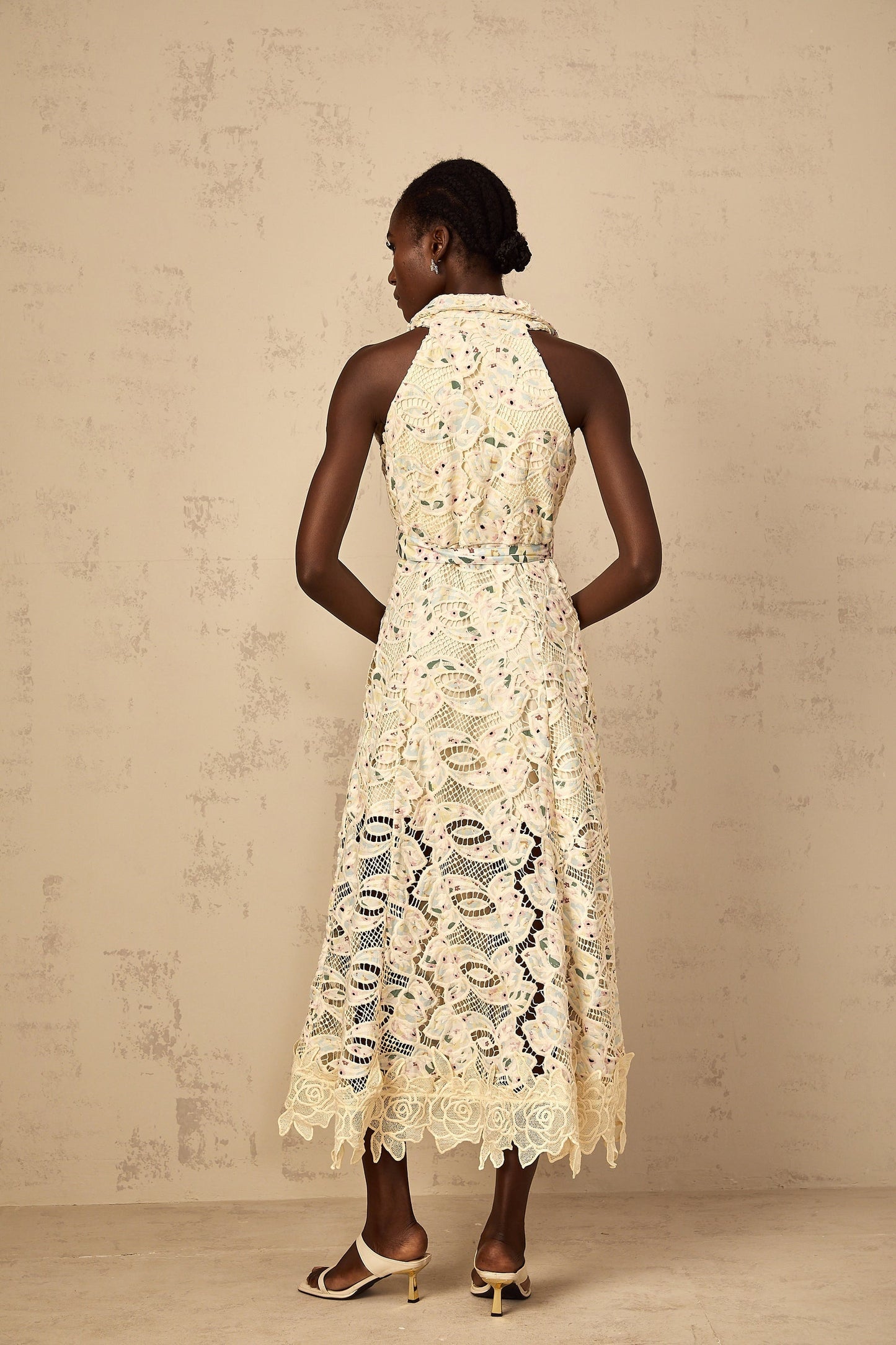 A woman wearing a floral embroidered midi dress with cutout details standing in a relaxed pose against a plain background