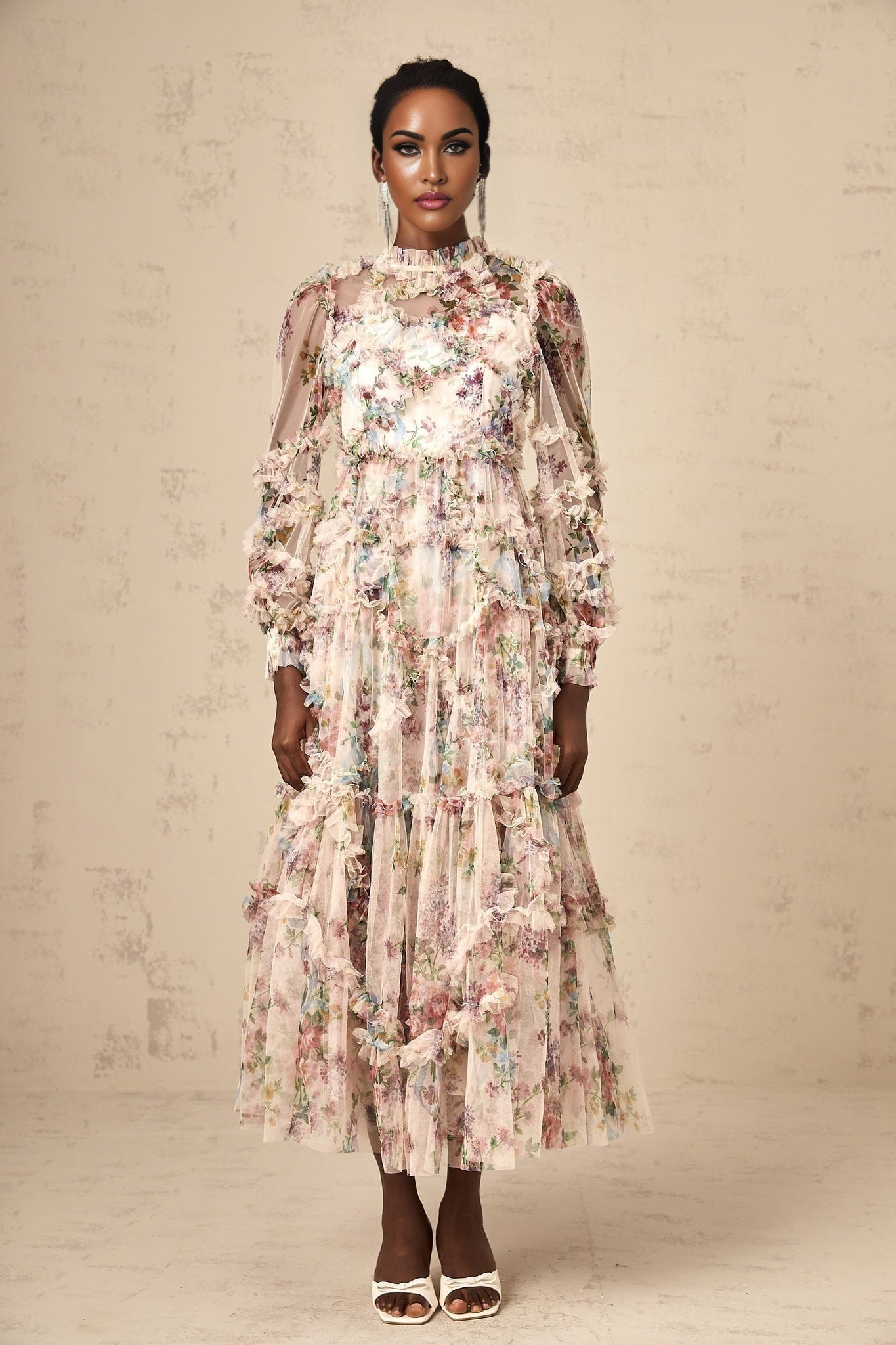 A woman wearing a floral patterned midi dress with ruffled details and a tulle skirt