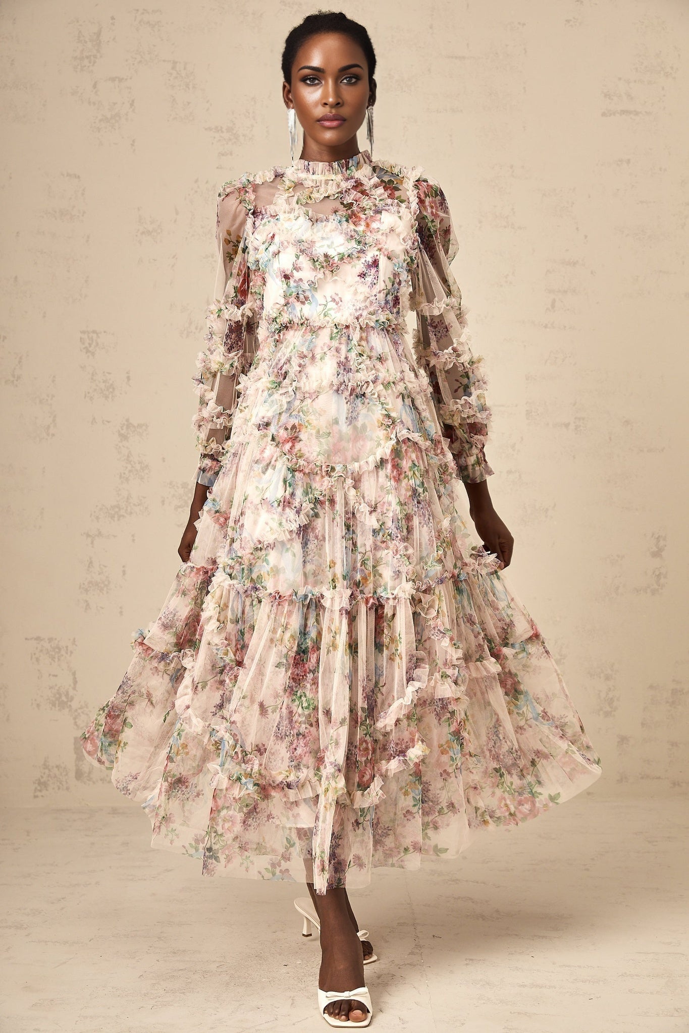A woman wearing a floral patterned midi dress with ruffled details and a tulle skirt