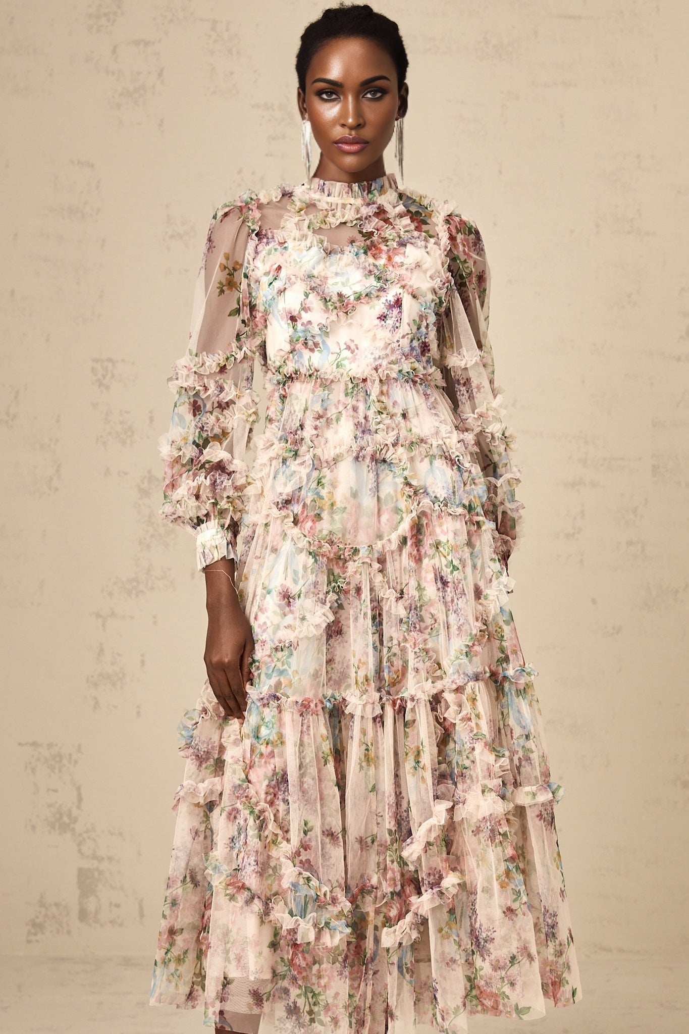 A woman wearing a floral patterned midi dress with ruffled tulle details and a delicate feminine design
