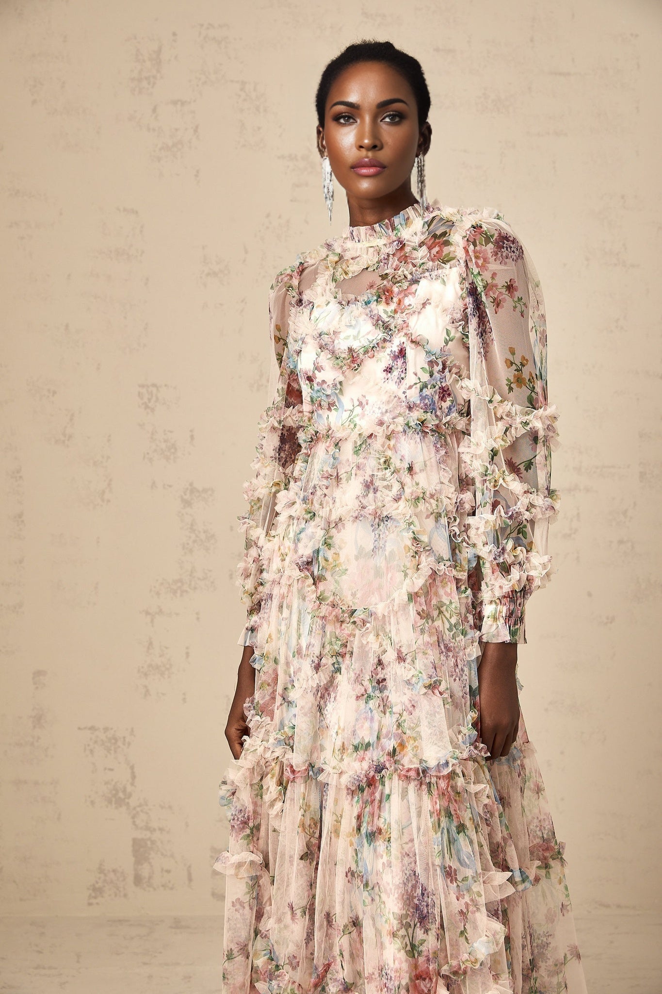 A woman wearing a floral patterned midi dress with ruffled tulle details and a delicate floral print