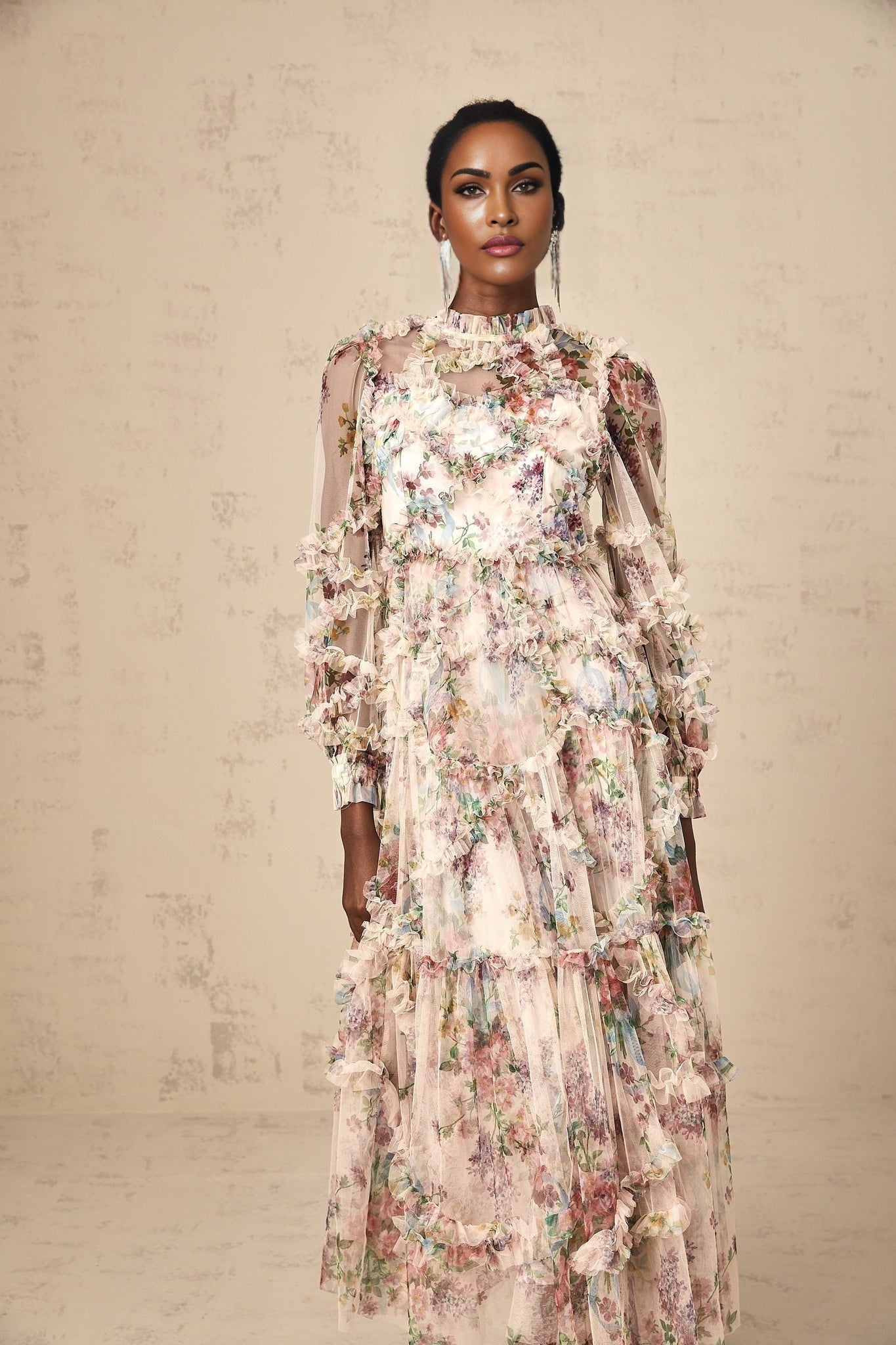 A woman wearing a floral patterned midi dress with ruffled tulle details and a feminine silhouette