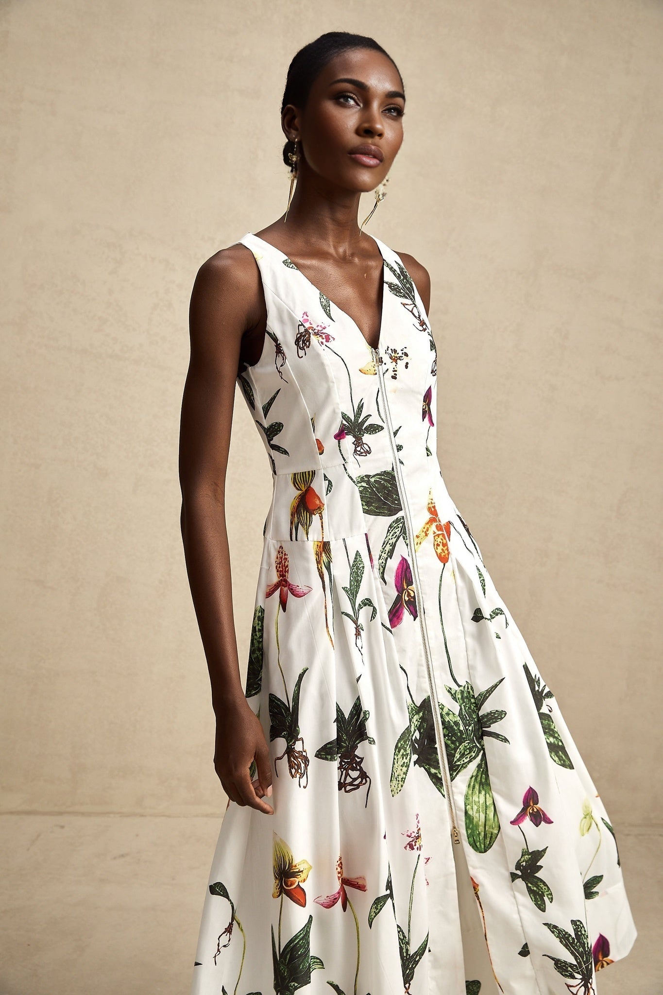 A woman wearing a floral print midi dress with a v neckline and short sleeves standing in a relaxed pose against a plain background