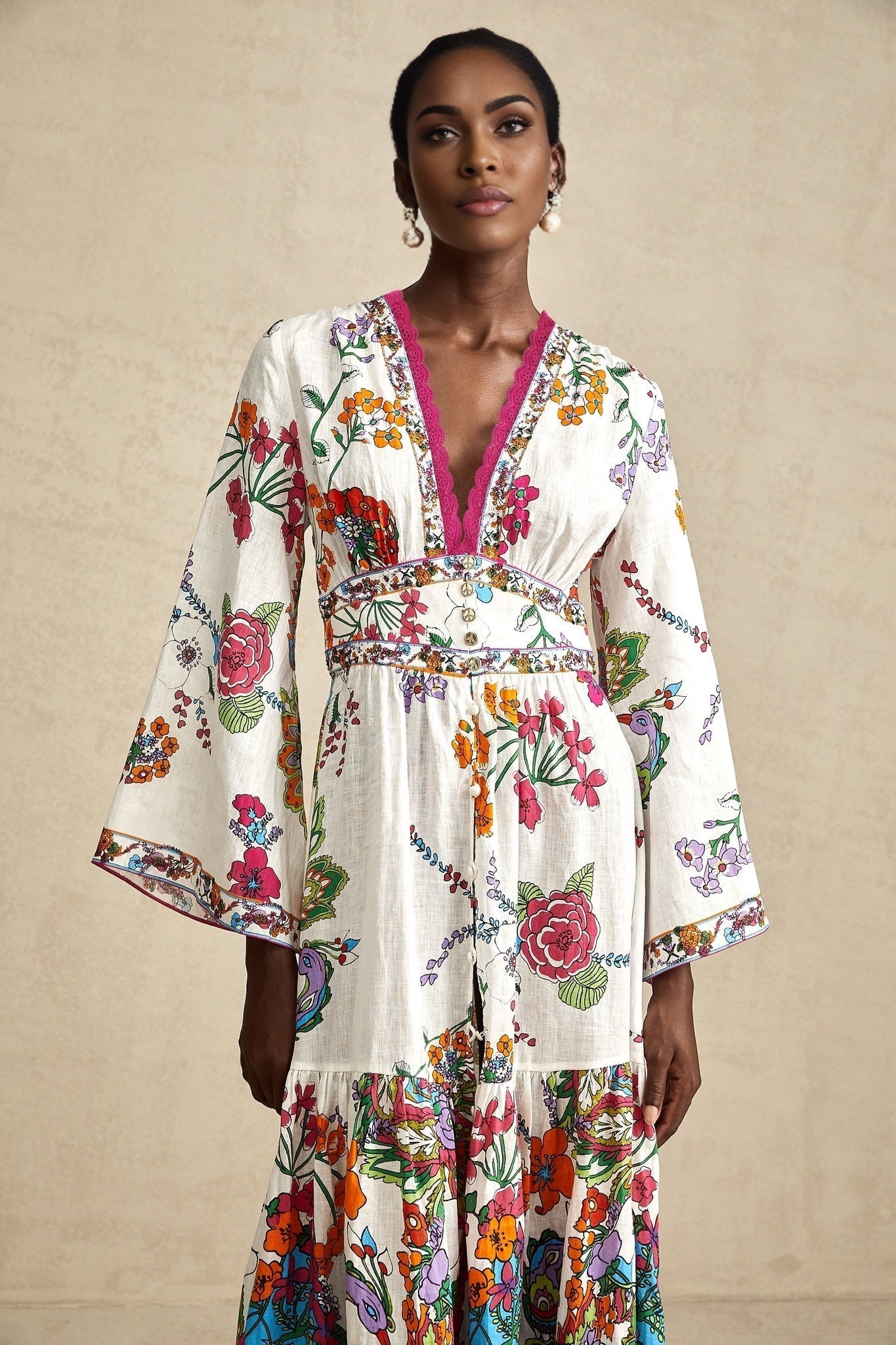 A woman wearing a floral print midi dress with a V neckline standing against a plain background