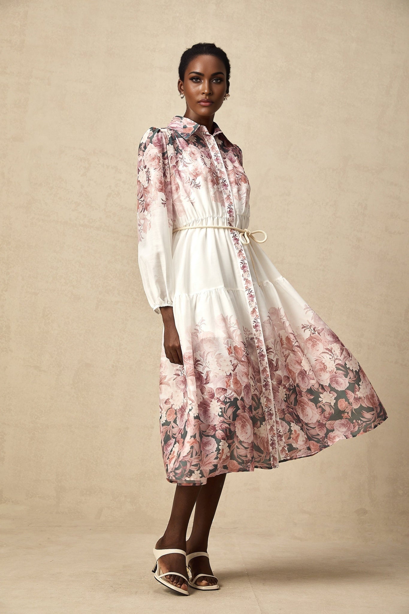 A woman wearing a floral print midi dress with lantern sleeves standing in a casual pose against a plain background