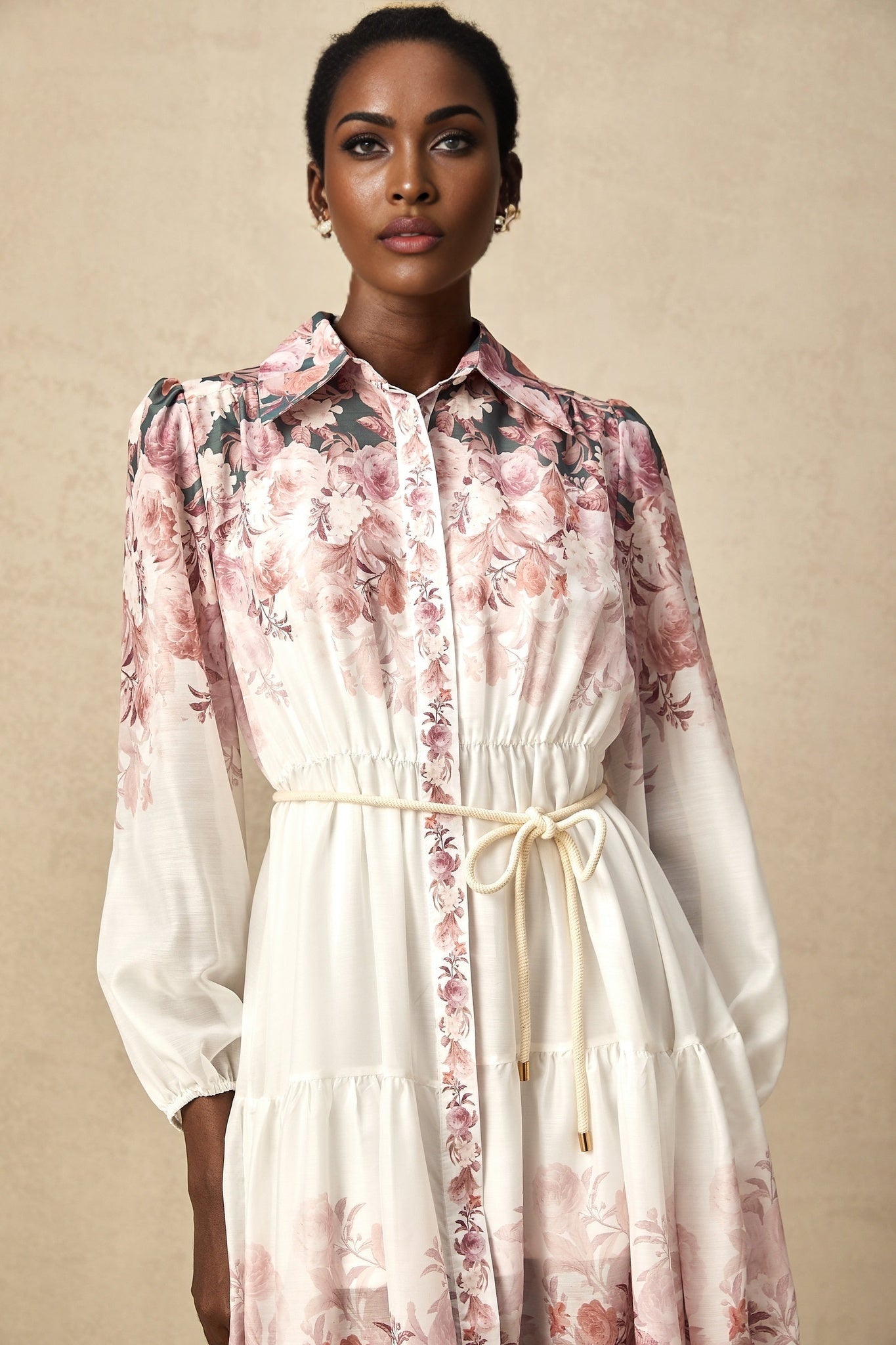 A woman wearing a floral print midi dress with lantern sleeves standing in a relaxed pose against a plain background