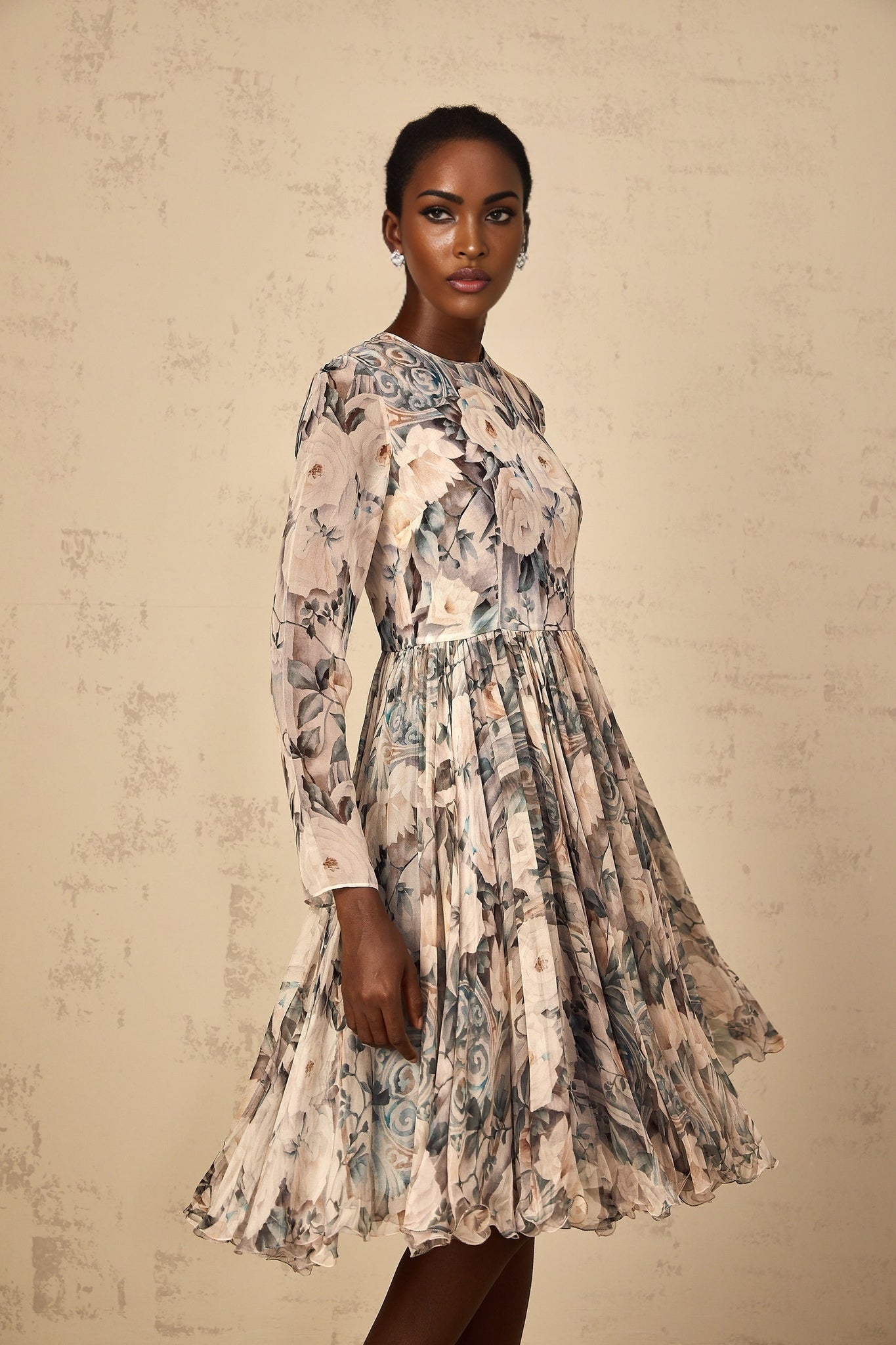 A woman wearing a floral print pleated chiffon midi dress with a colorful pattern standing in a casual pose