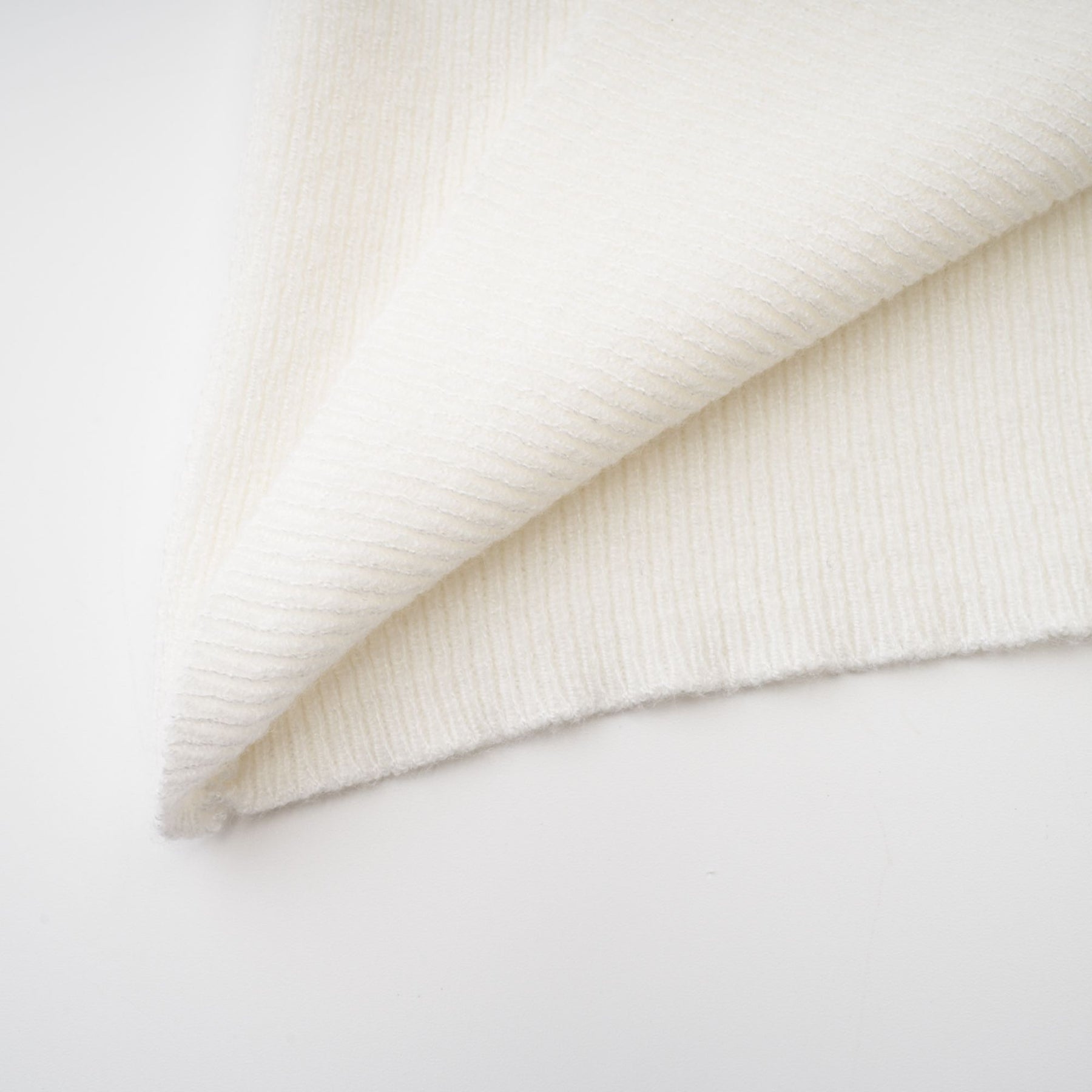 A woman wearing a formfitting knitted strapless top with long sleeves in a light color against a plain background