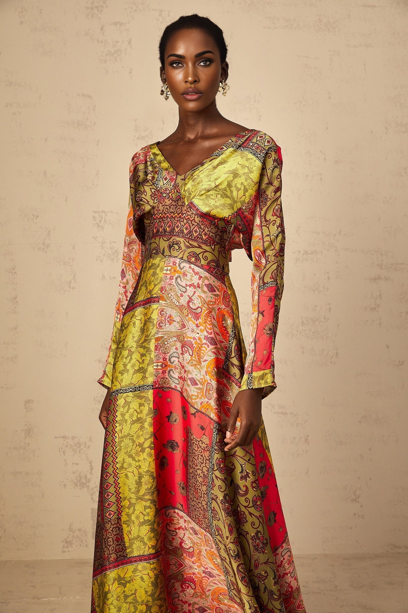 A woman wearing a green floral print midi dress with a flared skirt standing against a plain background