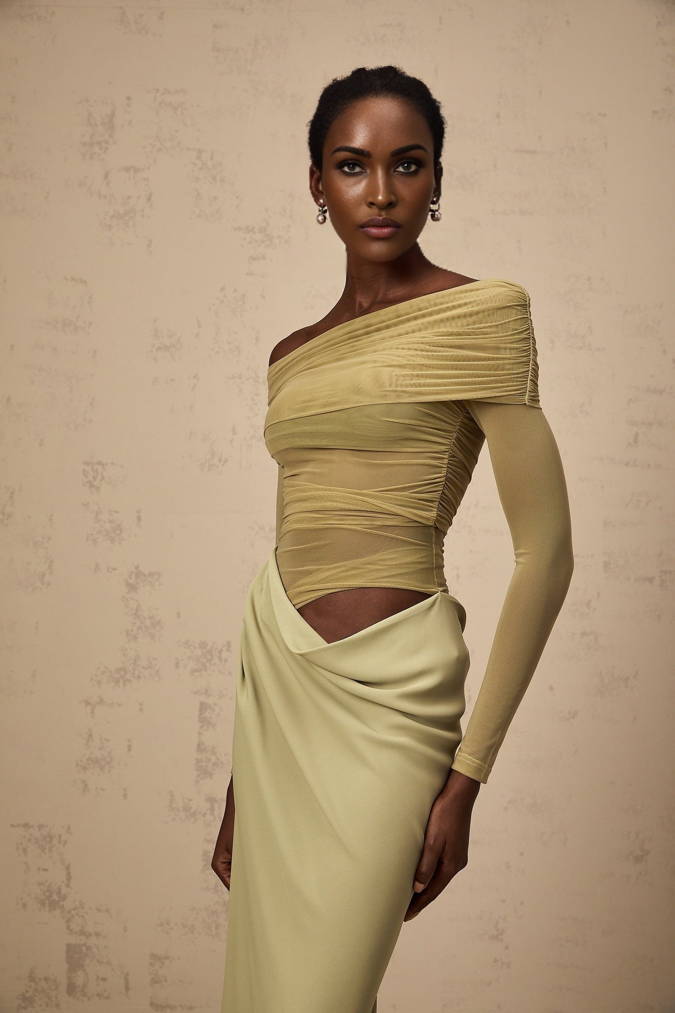 A woman wearing a green offshoulder midi dress with semisheer fabric standing in a relaxed pose