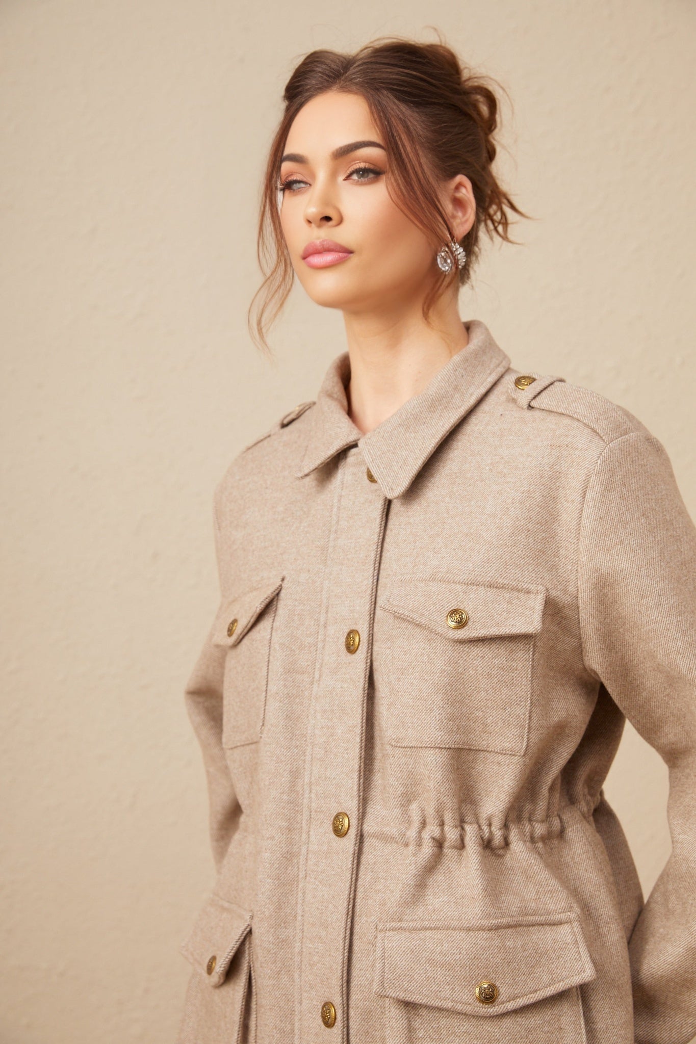 A woman wearing a khaki wool twill jacket paired with matching culottes standing against a plain background