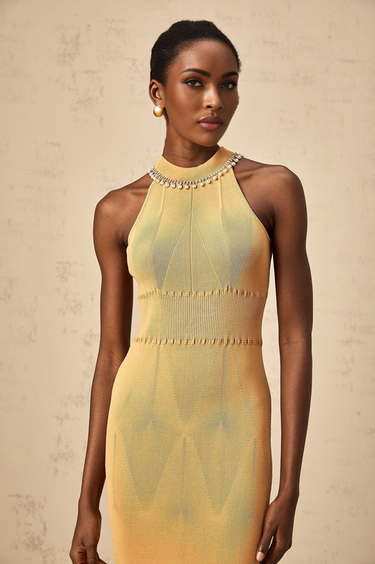 A woman wearing a knit midi dress with faux pearl embellishments along the neckline and sleeves The dress is form fitting and extends to mid calf length