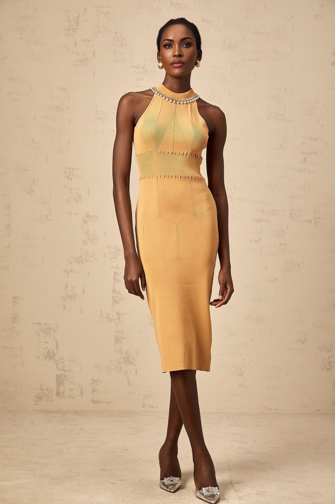 A woman wearing a knit midi dress with faux pearl embellishments throughout the fabric