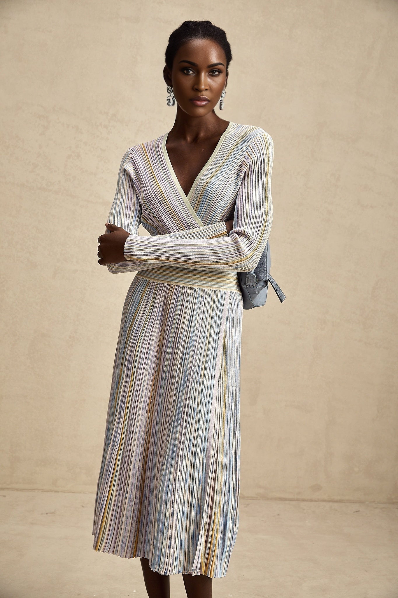 A woman wearing a knitted midi dress with vertical stripes in the style of Amelie standing in a relaxed pose against a plain background