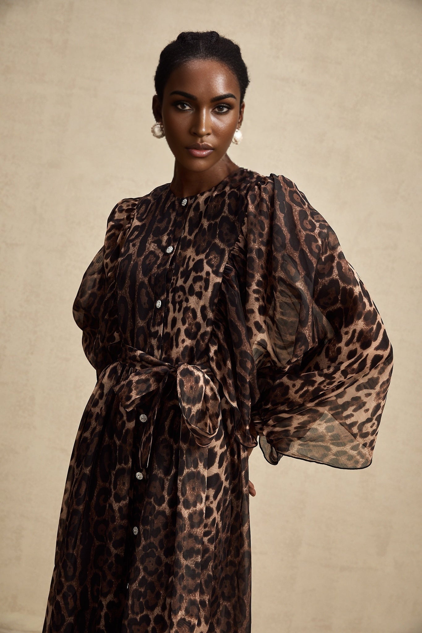 A woman wearing a leopard print midi dress with a single breasted design and long sleeves