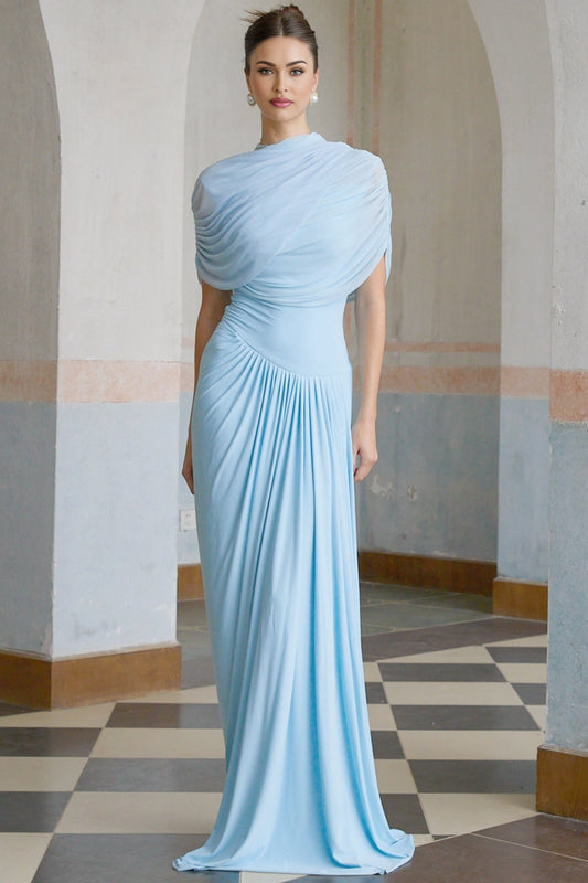 A woman wearing a light blue asymmetric pleated maxi dress with a flowing skirt and one shoulder strap