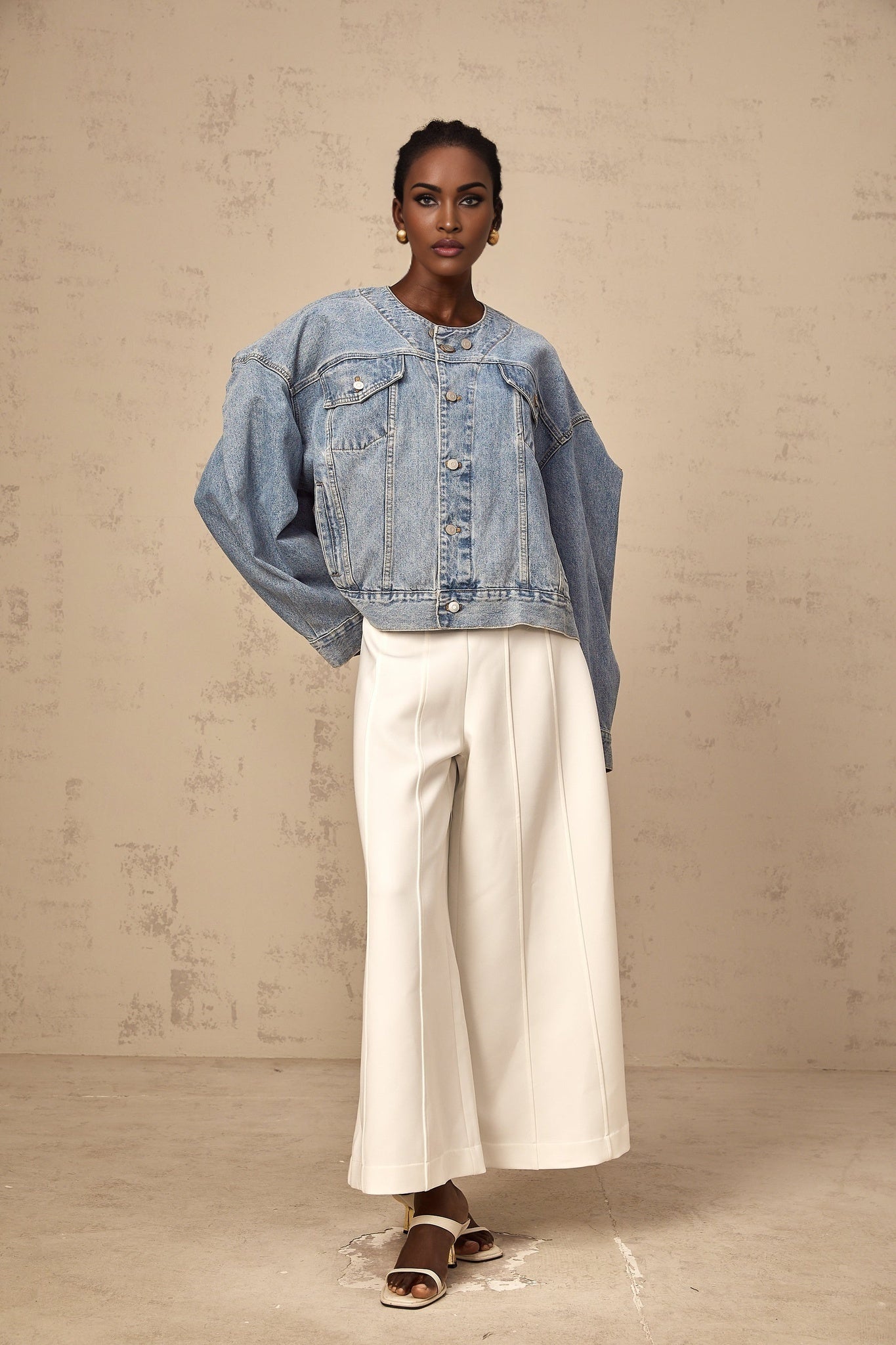 A woman wearing a light blue collarless denim jacket with long sleeves and front pockets