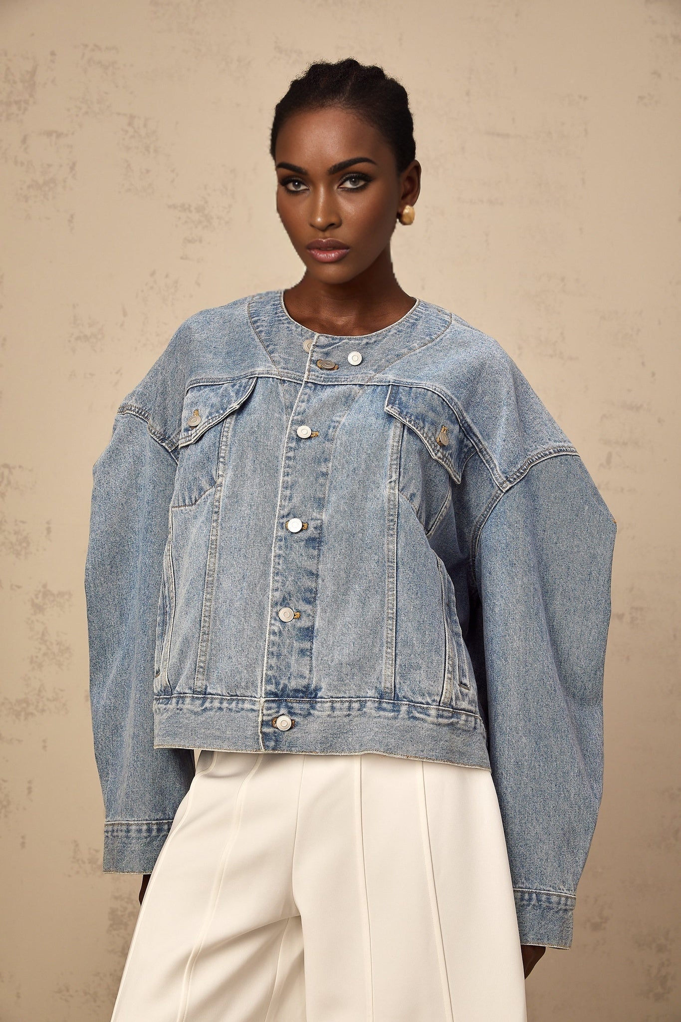 A woman wearing a light blue collarless denim jacket with long sleeves and front pockets