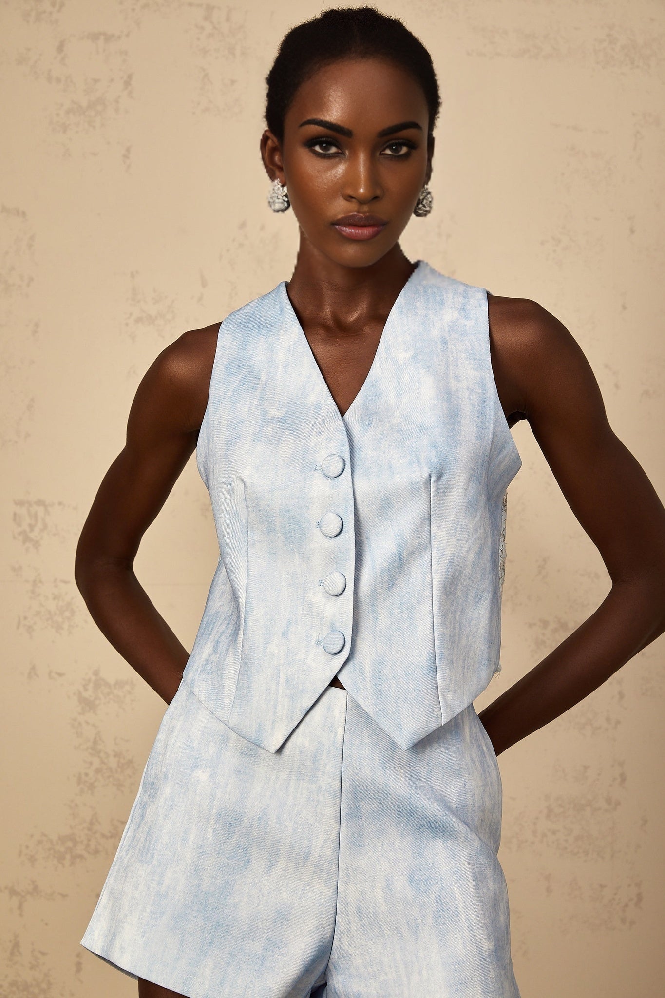A woman wearing a light blue denim matching set consisting of a cropped jacket and high waisted jeans with a faded effect