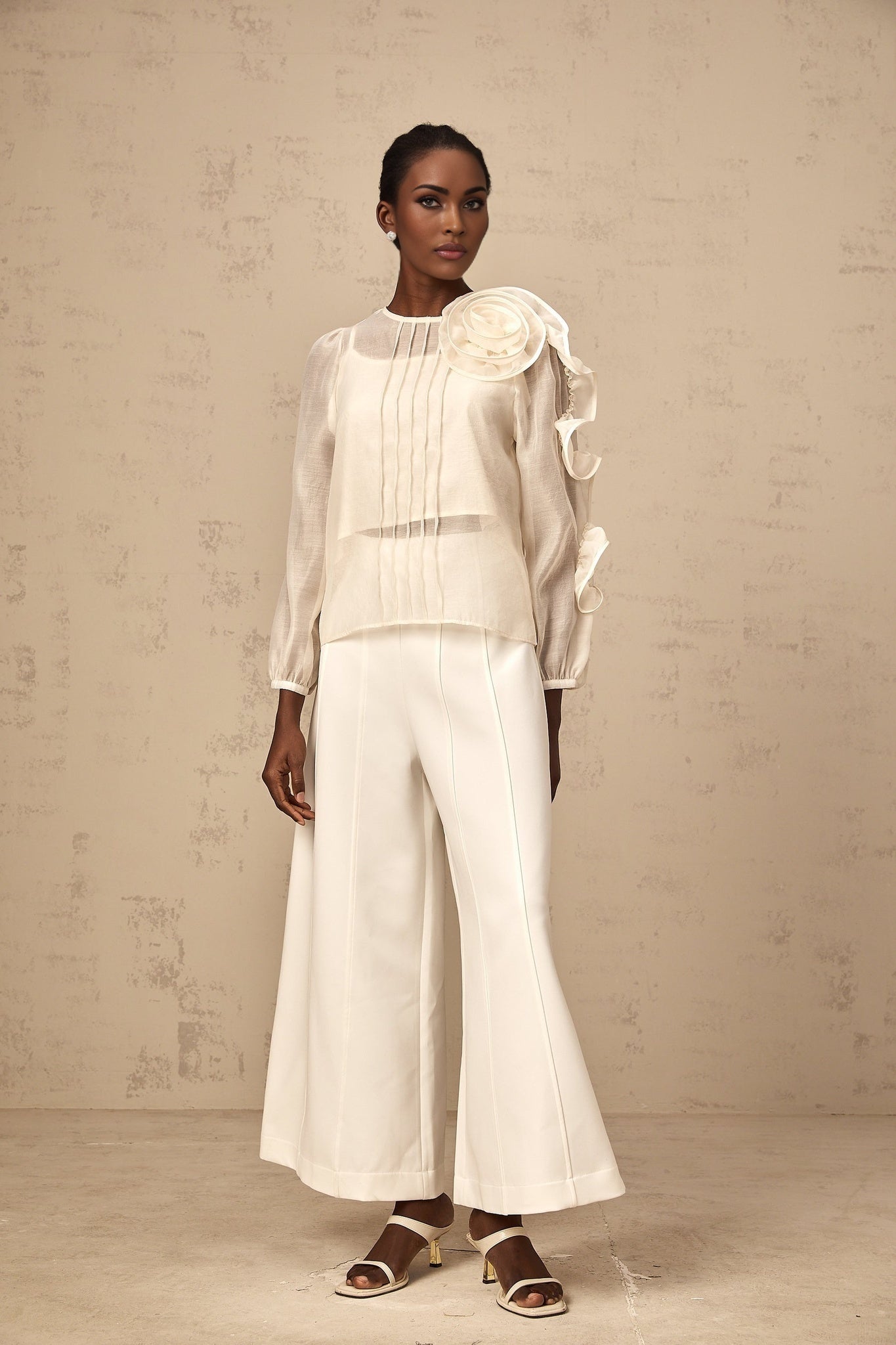 A woman wearing a lightcolored sheer blouse with delicate three dimensional floral details