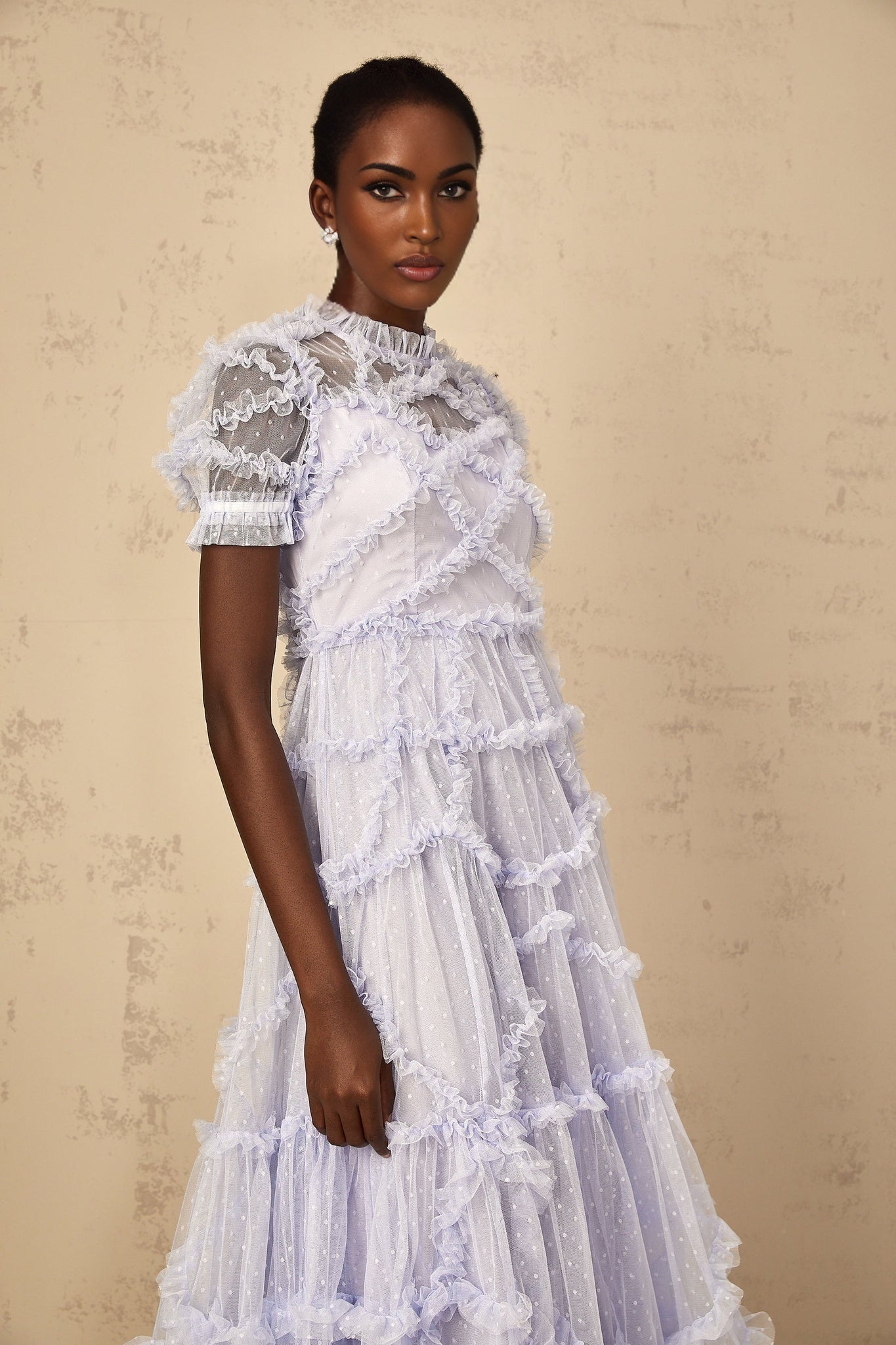 A woman wearing a long blue maxi dress with white polka dots and ruffled tulle details