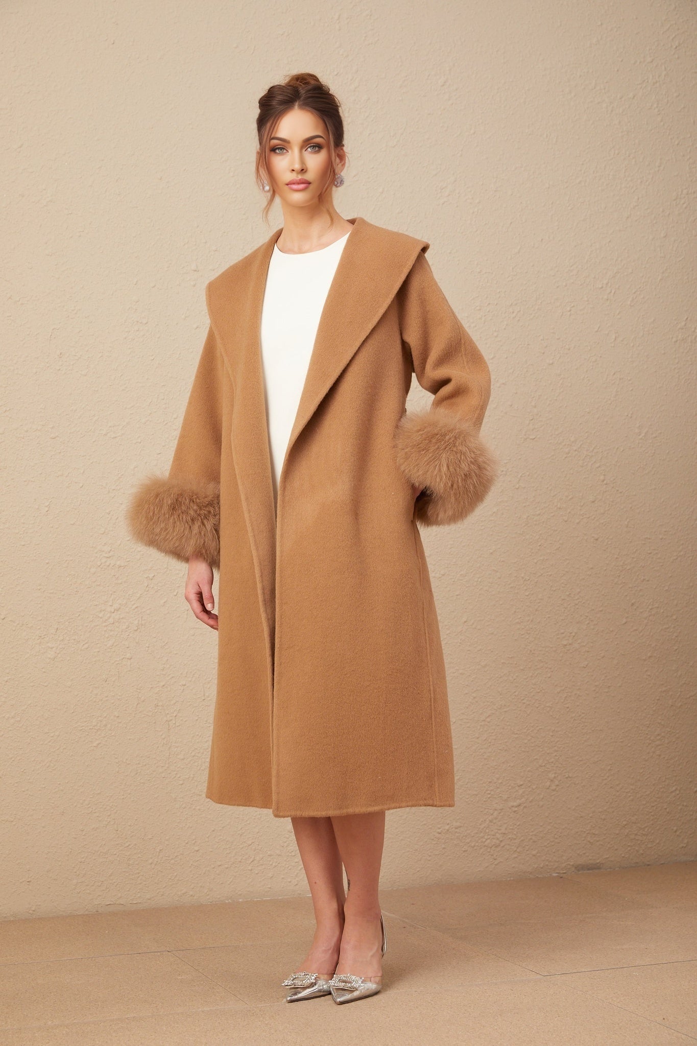 A woman wearing a long brown felted wool wrap overcoat with a loose draped style and open front