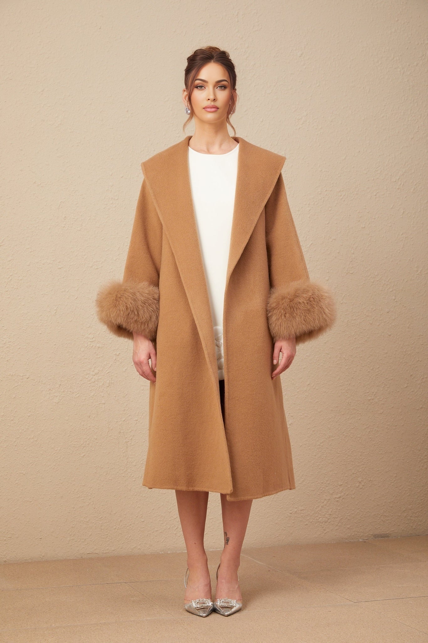 A woman wearing a long brown woolen wrap coat with a felted texture standing against a neutral background