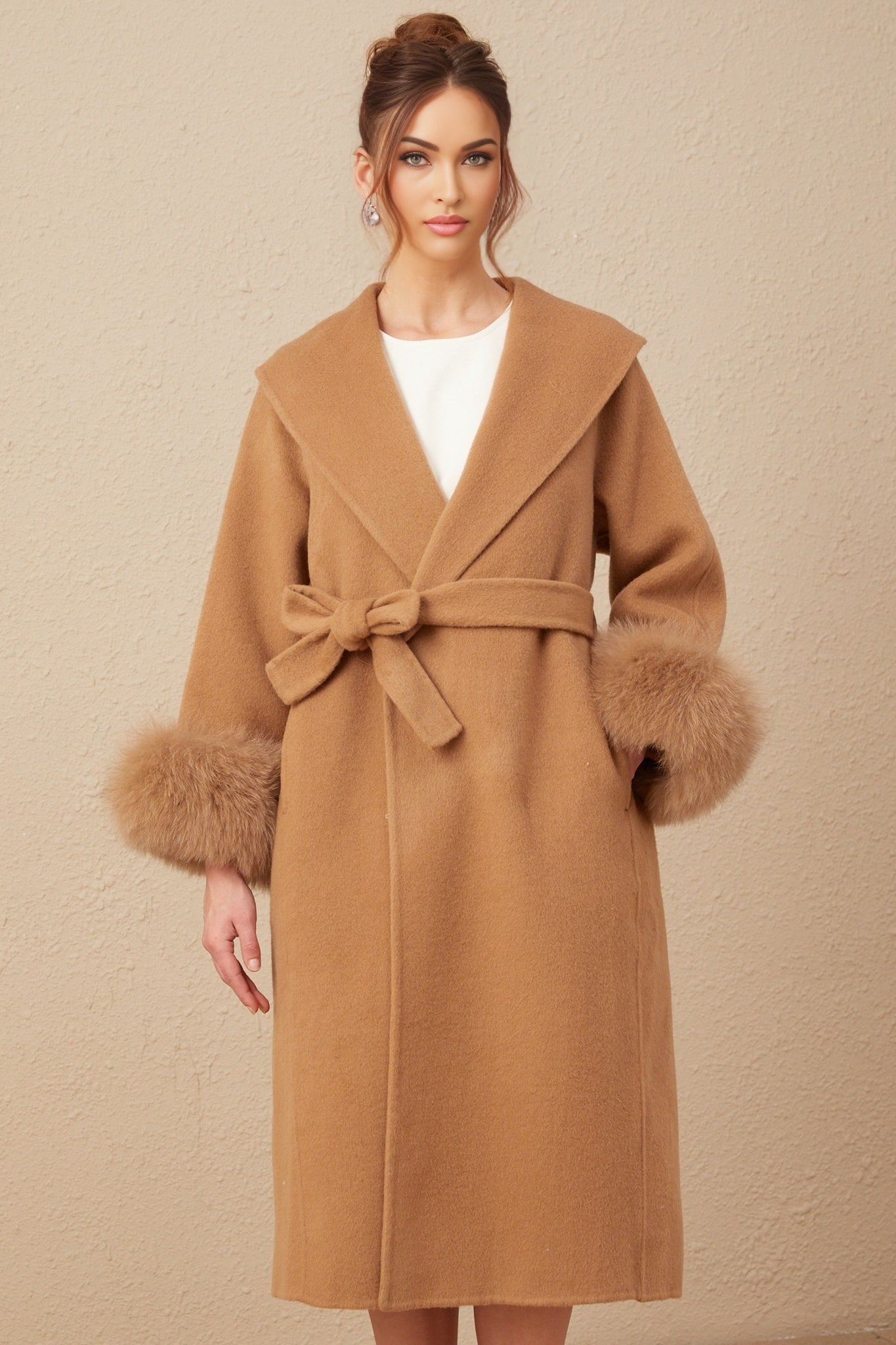 A woman wearing a long brown woolen wrap overcoat with a felted texture standing against a neutral background