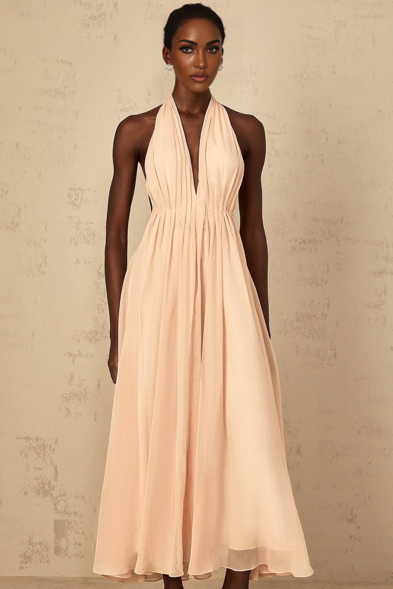 A woman wearing a long flowing halterneck maxi dress with shirred bodice and tulle skirt