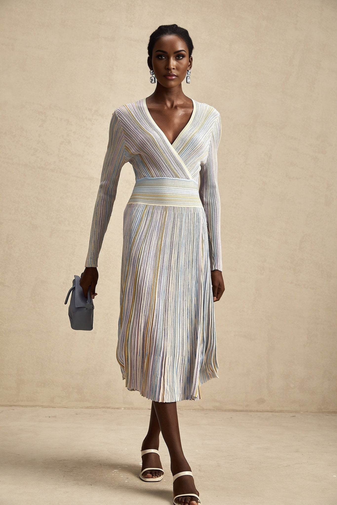 A woman wearing a long knitted midi dress with vertical stripes standing in a casual pose The dress features alternating light and dark stripes running from top to bottom and has a fitted silhouette