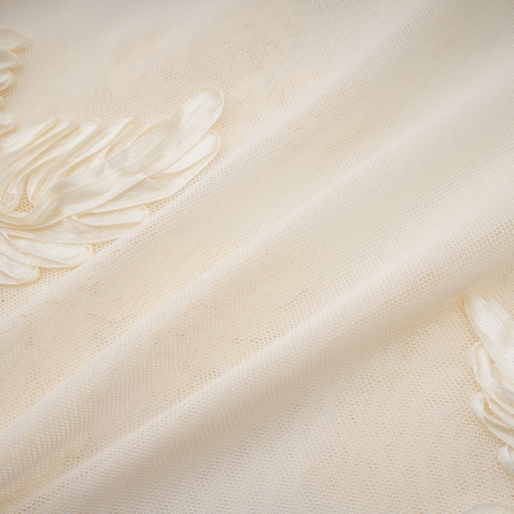 A woman wearing a long neutral colored offshoulder maxi dress with embroidery details standing in a relaxed pose